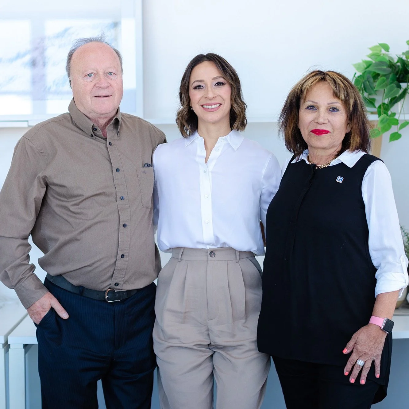 Three people standing together smiling.