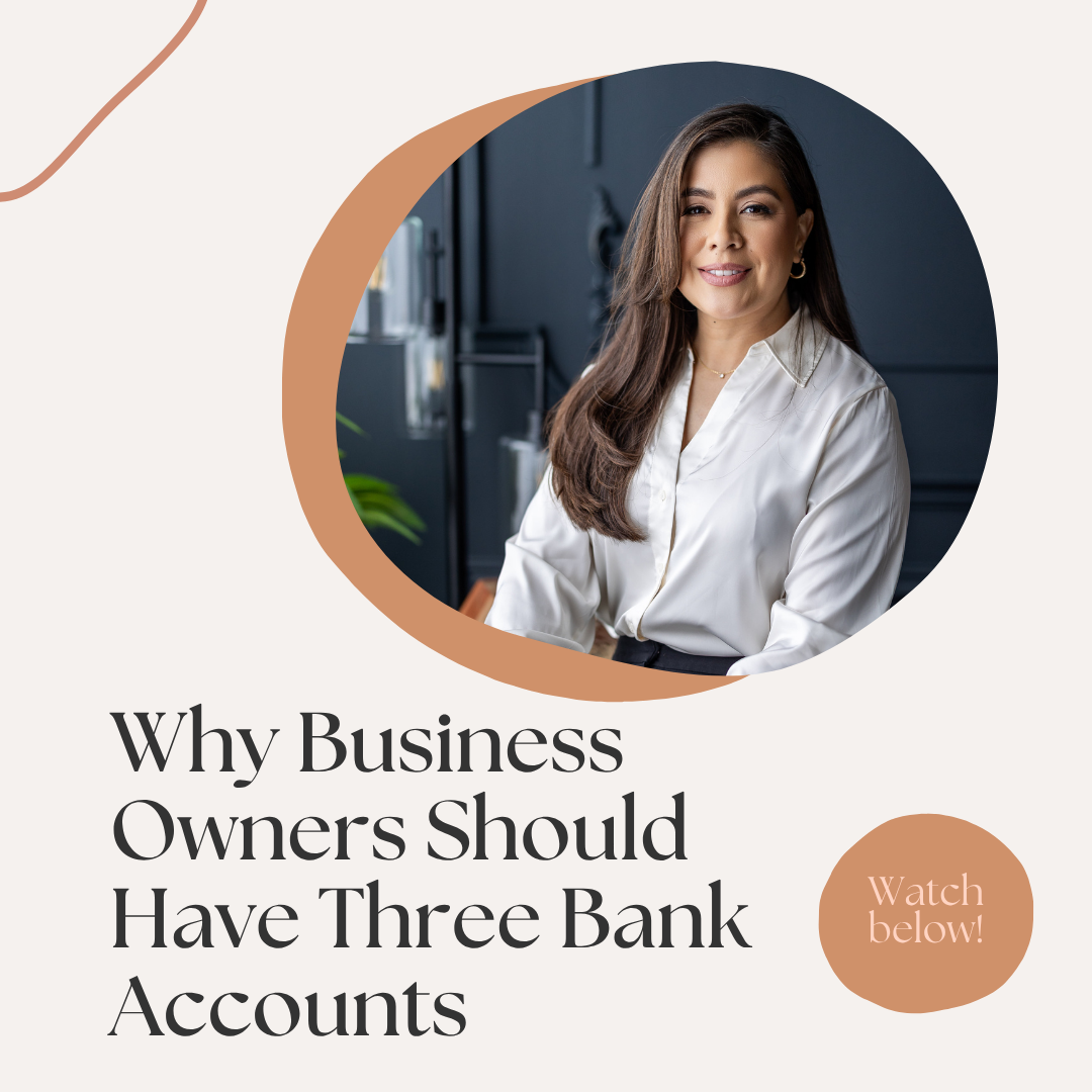 A woman with long brown hair, wearing a white blouse, smiling, sitting in a modern office with dark walls and plants.
