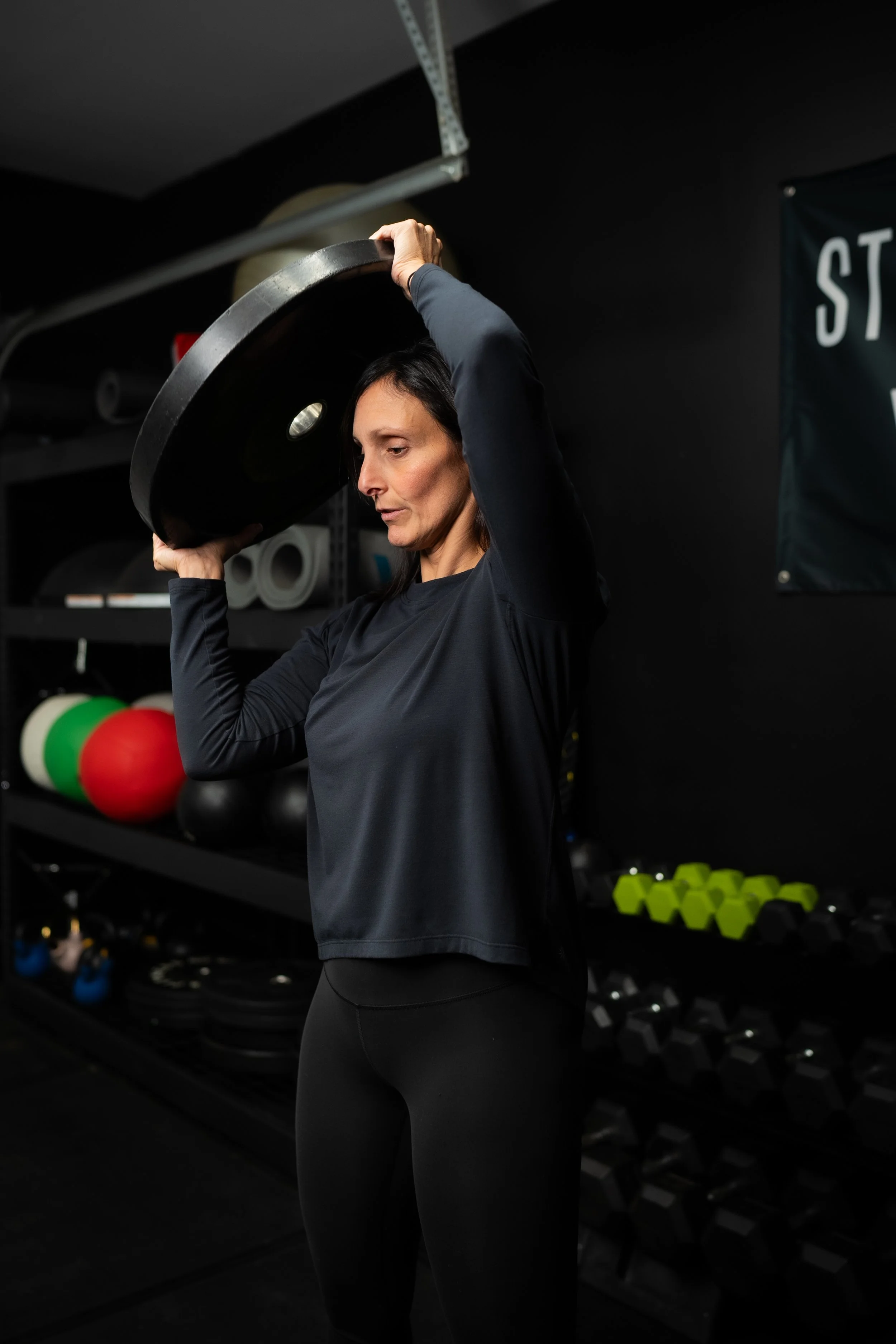 A woman lifting a weight plate during a workout in a gym.