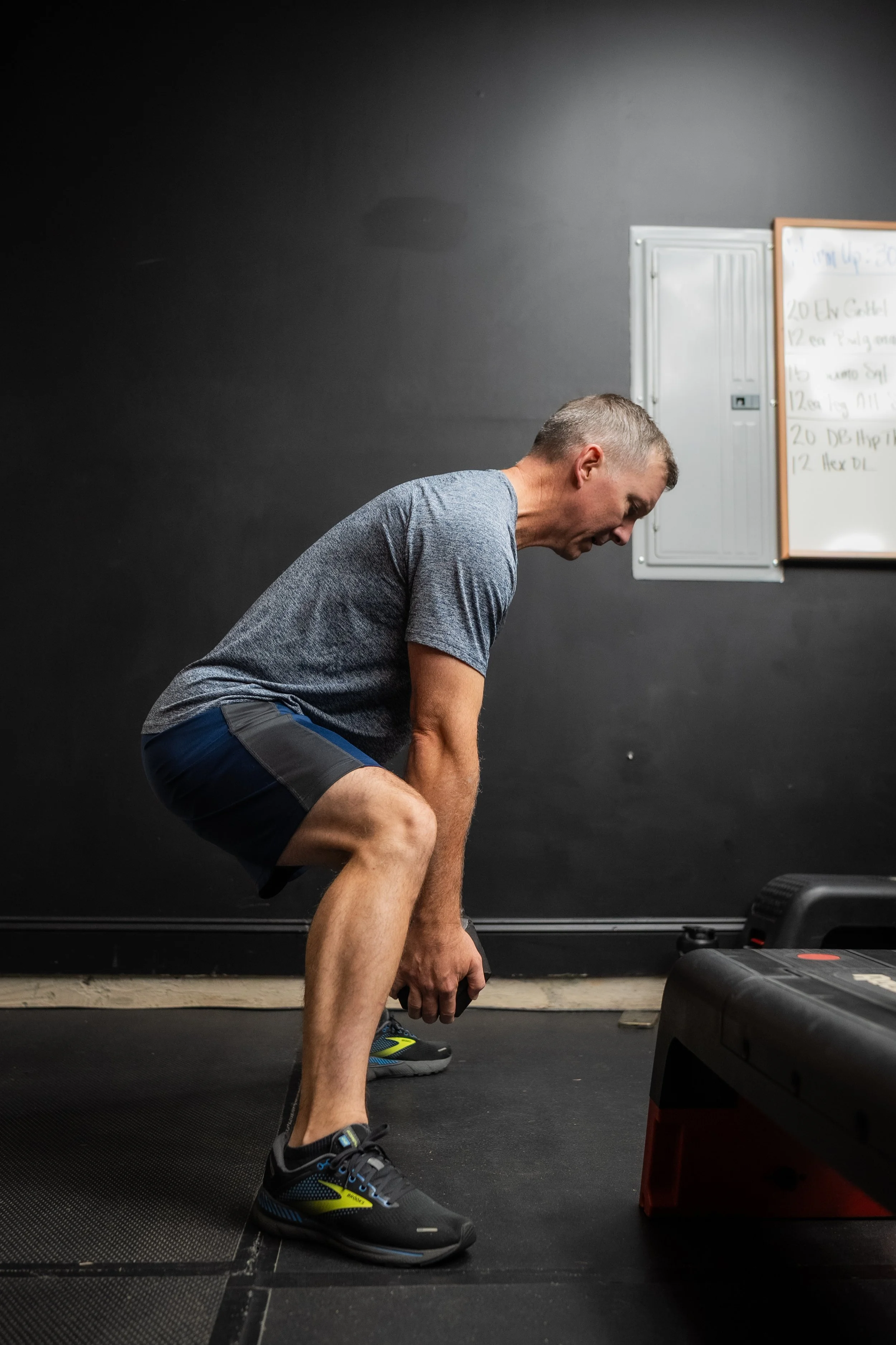 A man in athletic clothing performing a squat exercise in a gym.