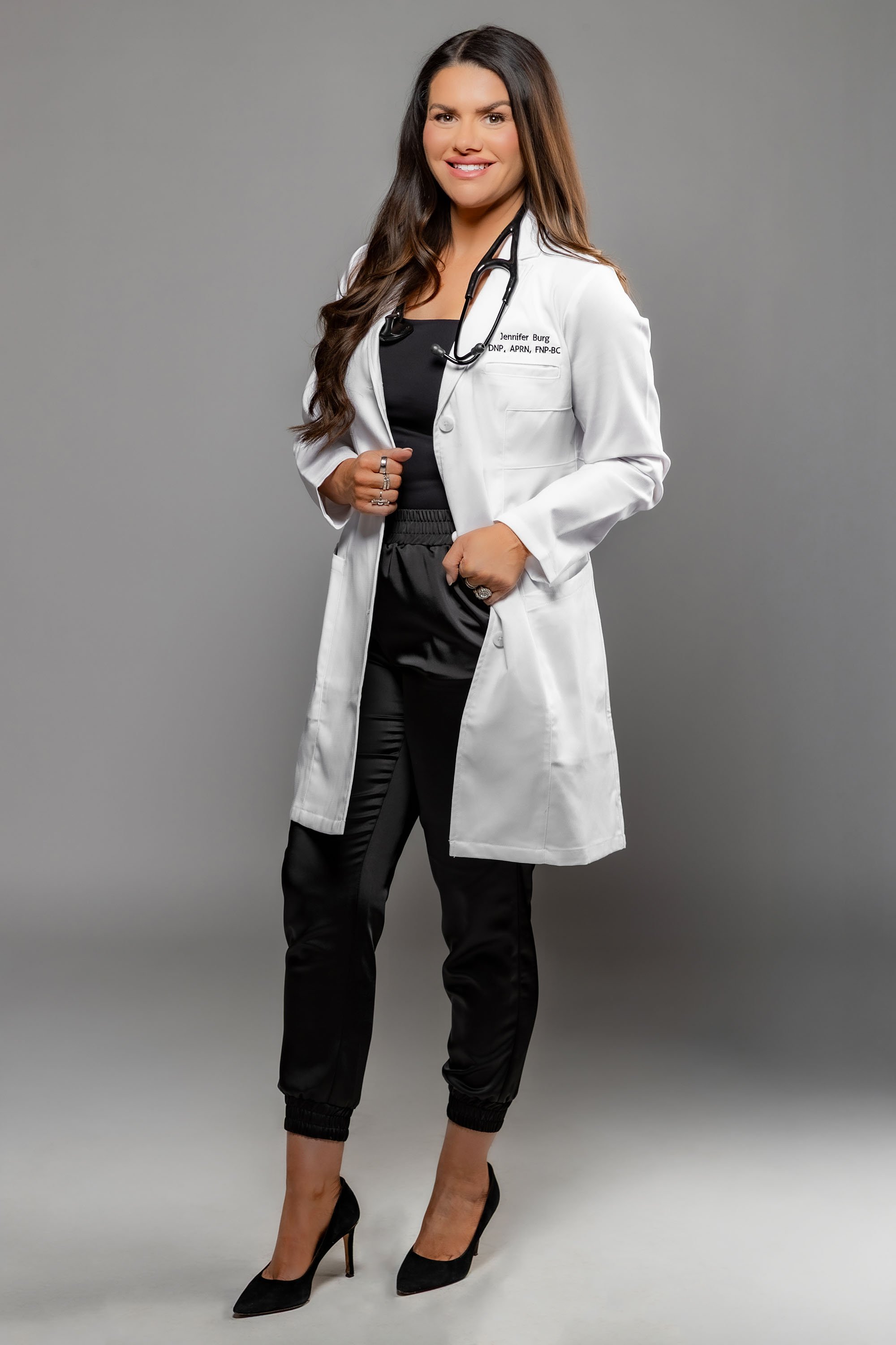 Dr. Jenn Burg standing in a white coat smiling