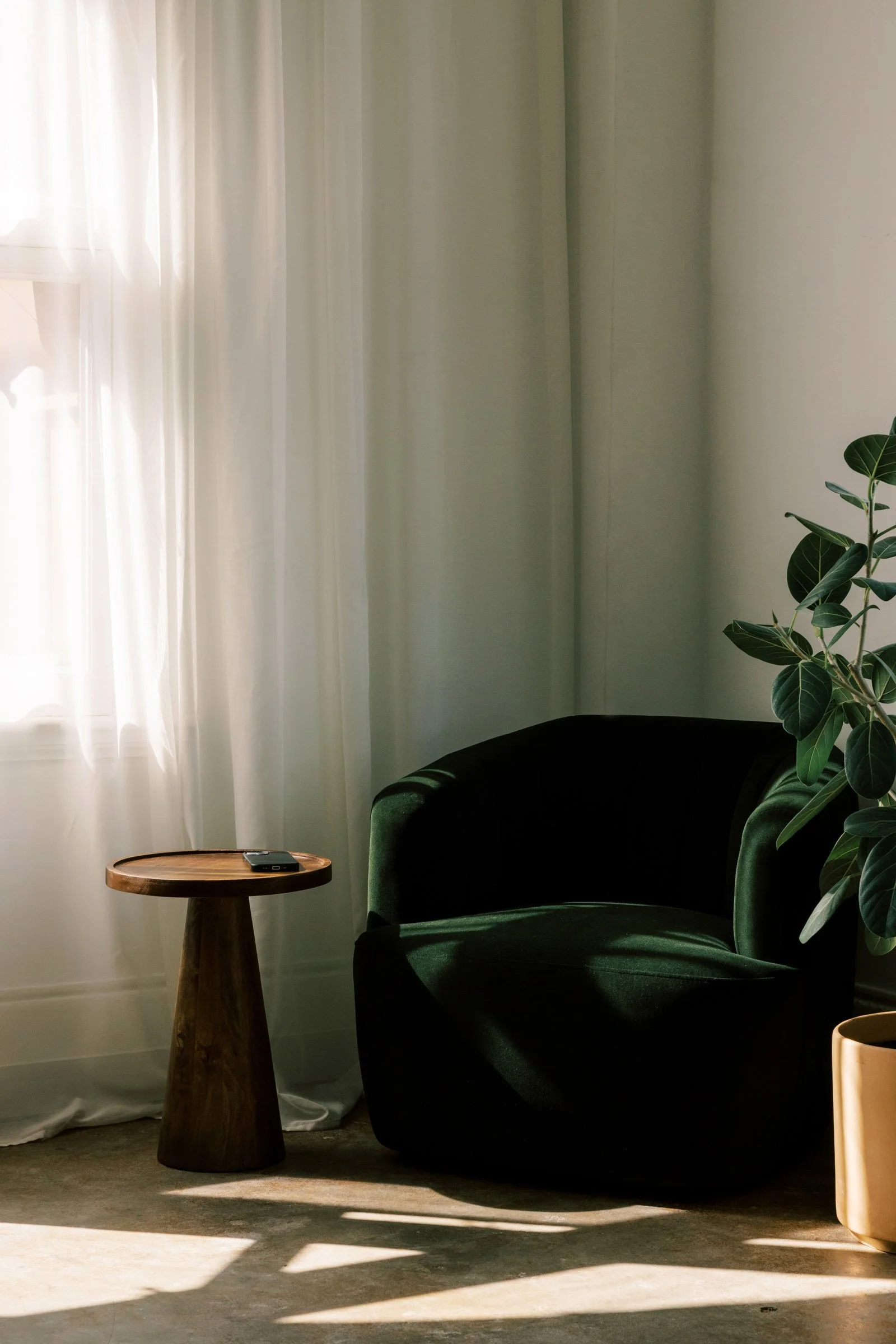 Green velvet chair next to window with sheer curtains