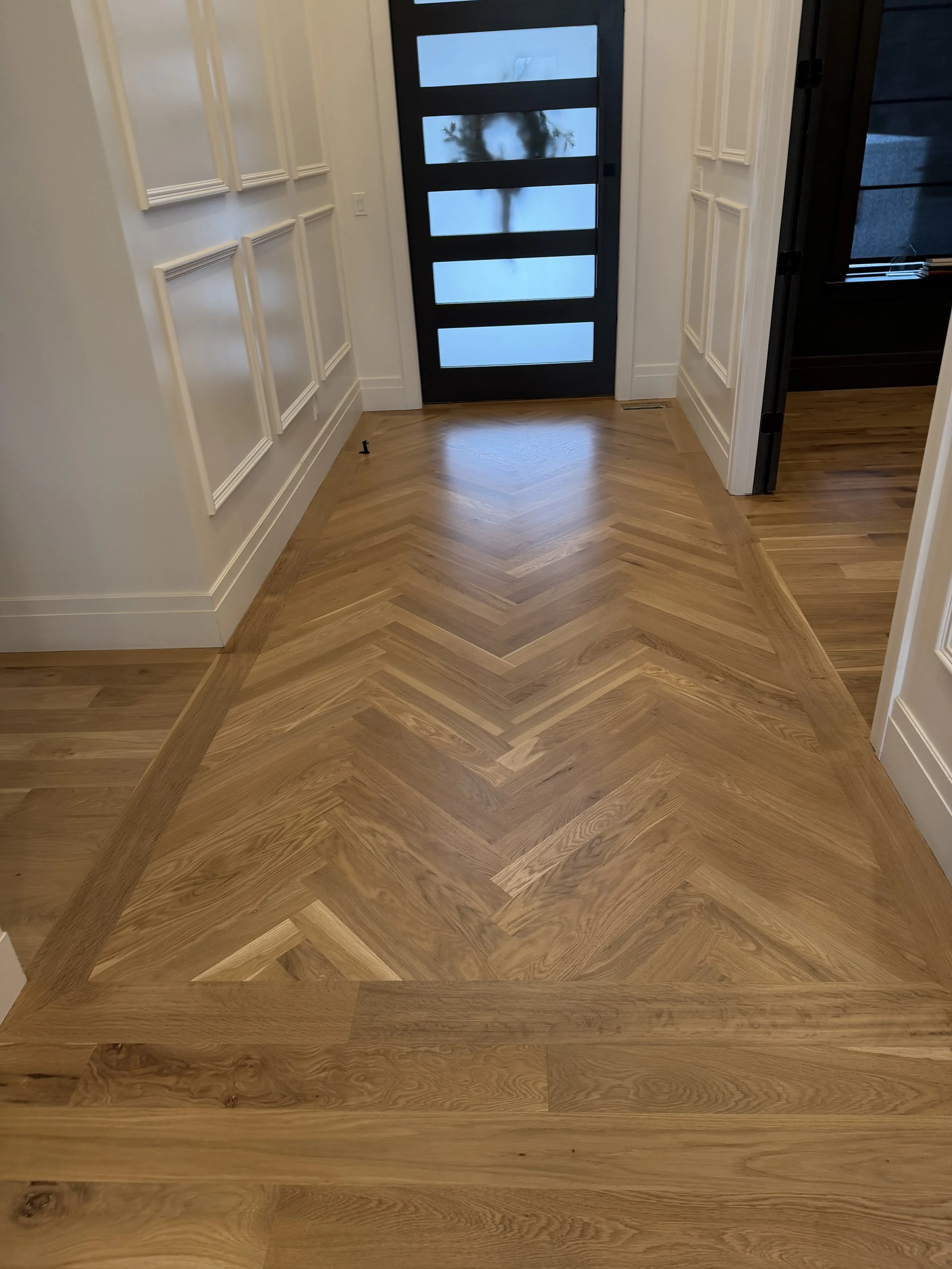 Refinished white oak herringbone hardwood floors at an entryway