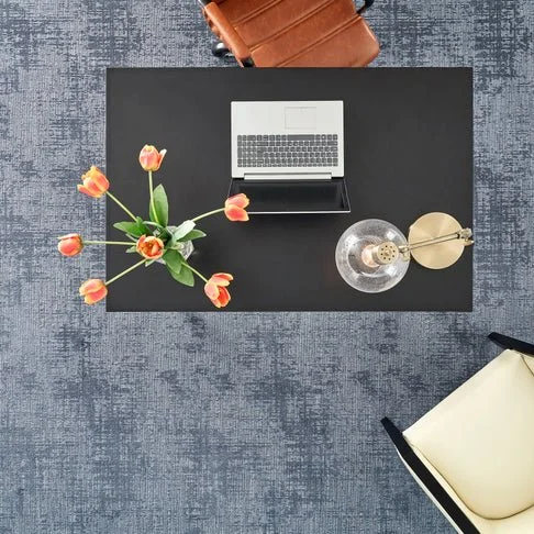 Aerial view of a working desk, with a laptop, lamp, and small vase of flowers.