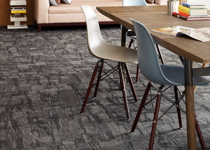 Solution Q Nylon carpet tile by Shaw; the image shows a commercial space with a table and set of chairs with a couch in the background.