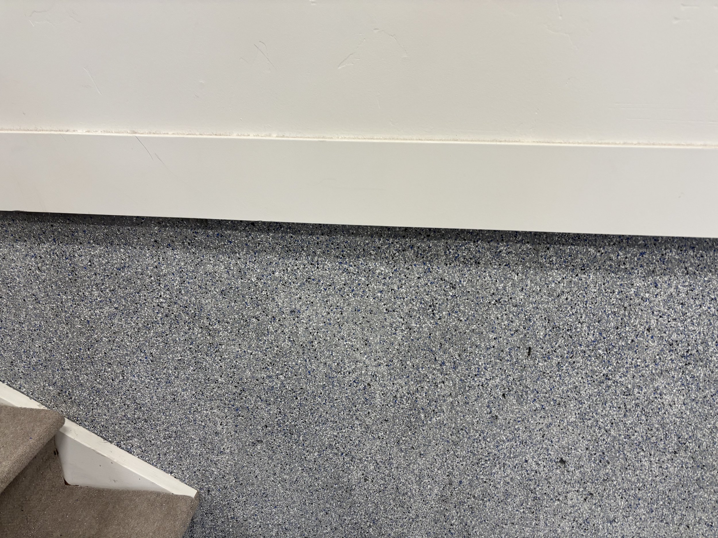 Garage epoxy flecks going up the wall. Up close shot, also shows portion of garage stair case