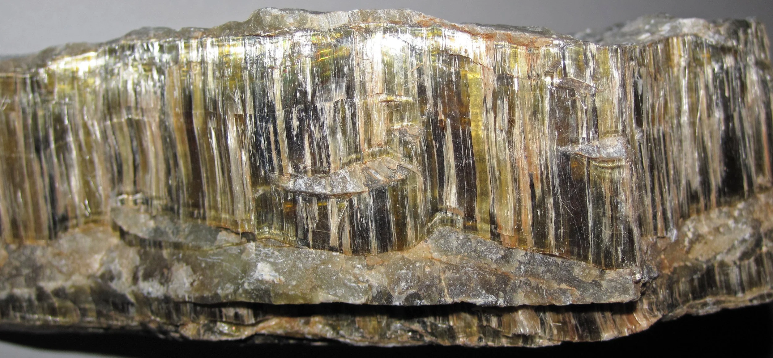 A large chunk of Chrysotile Asbestos, with green, black, white, and gray strips going down the side. Clicking on the image will take you to the image source.
