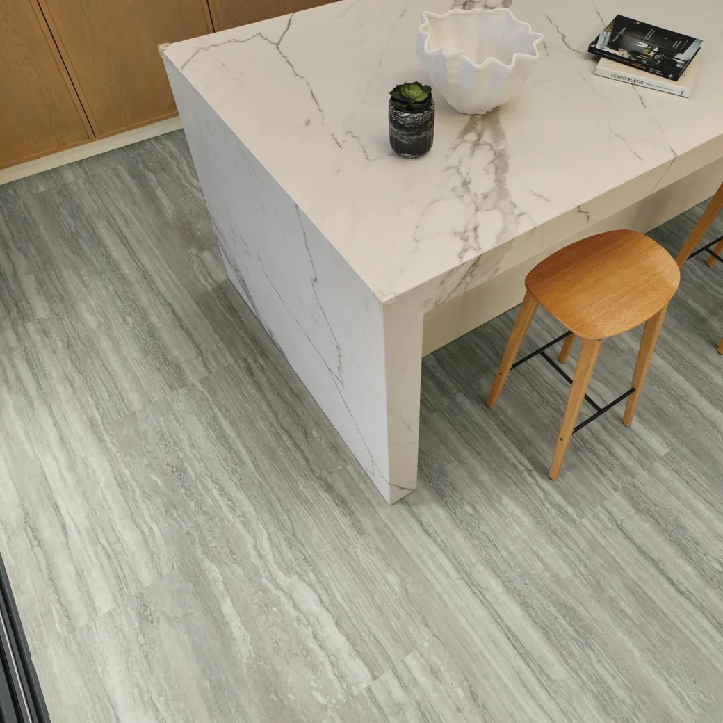 Marble countertop with a waterfall edge touching a gray travertine floor. 