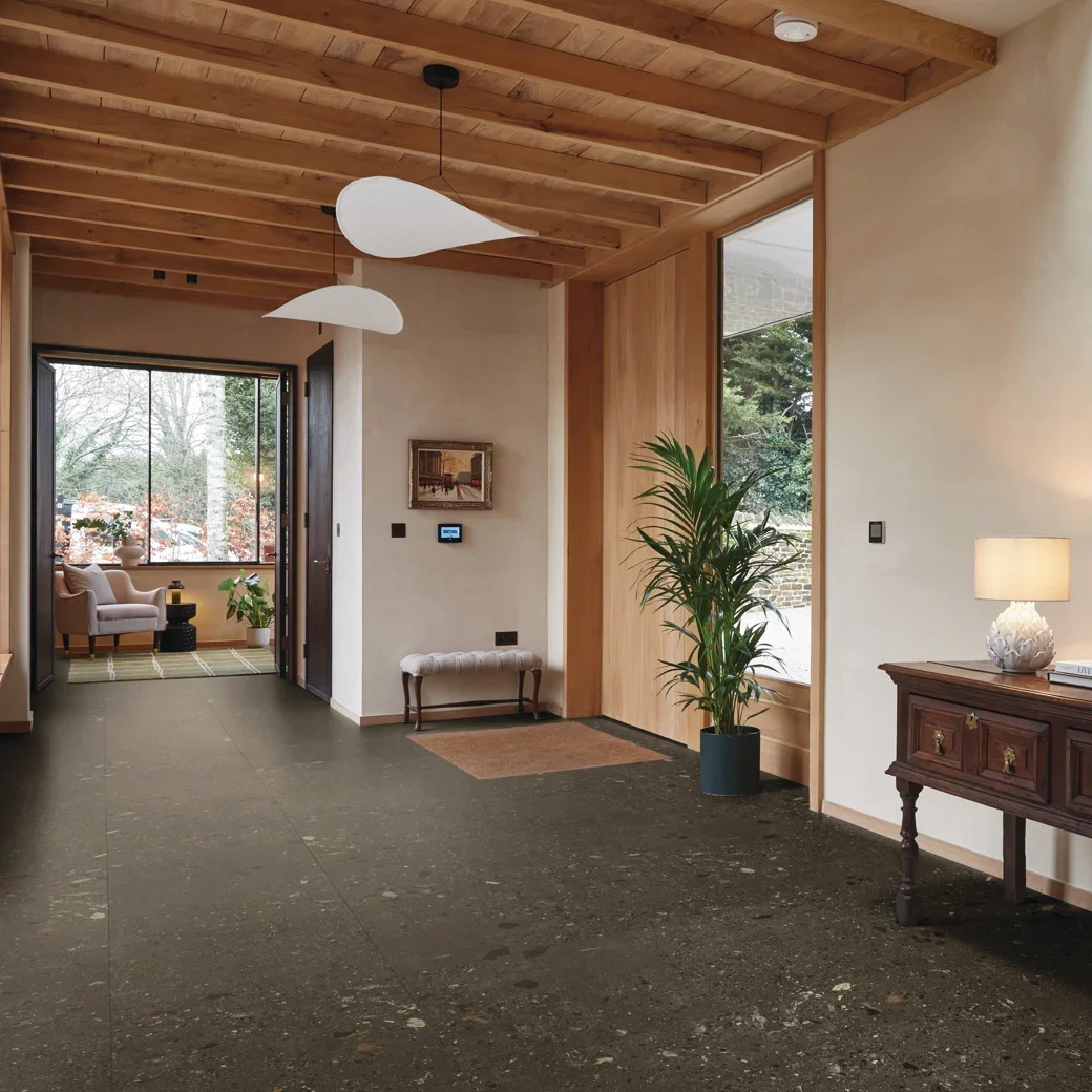 Home entryway with a wood plank ceiling matching the light wood of the door. The entryway leads to an office seating area one away and a hallway the other. 