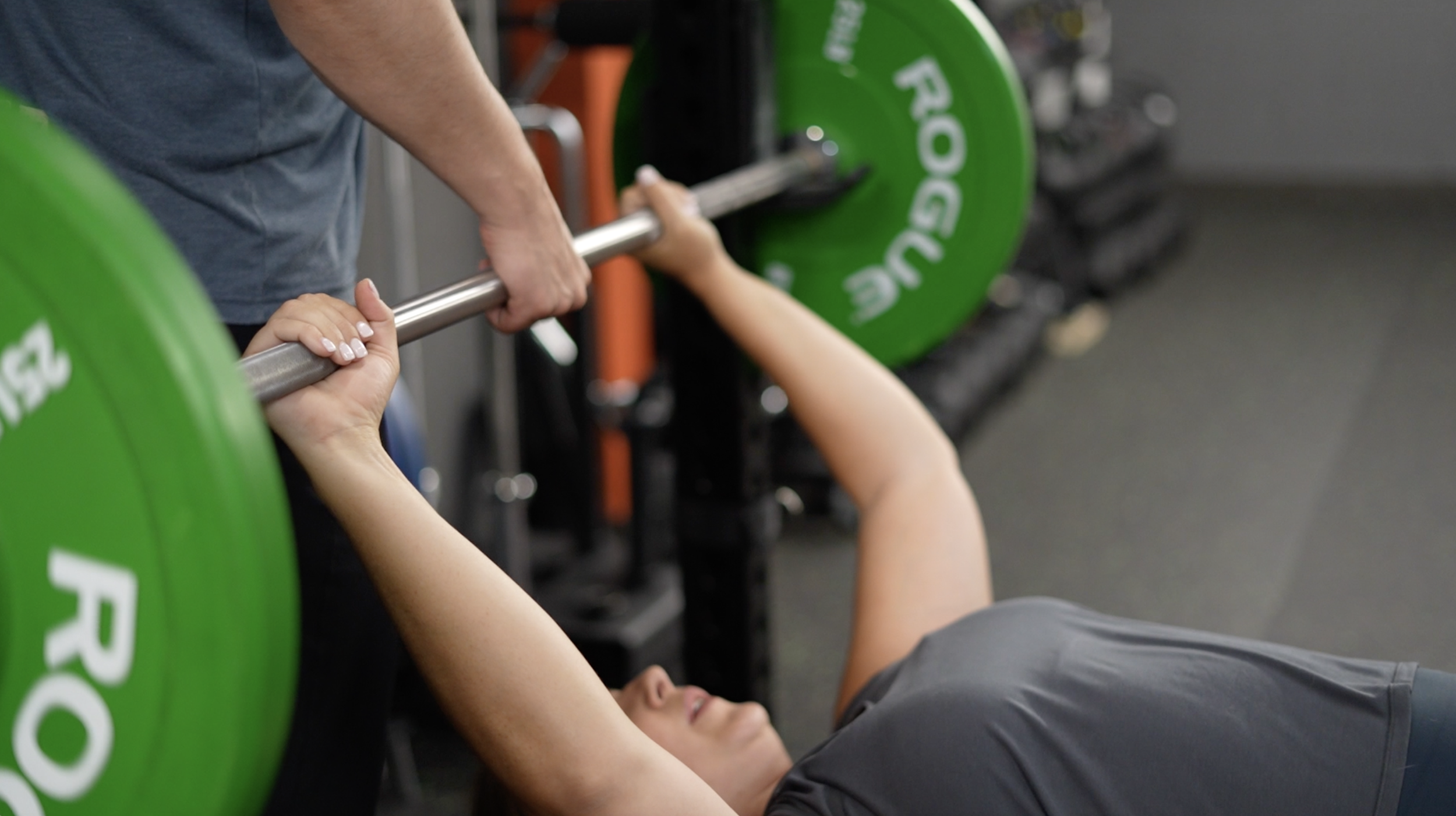 a young female lying supine on a weight bench preparing to bench press