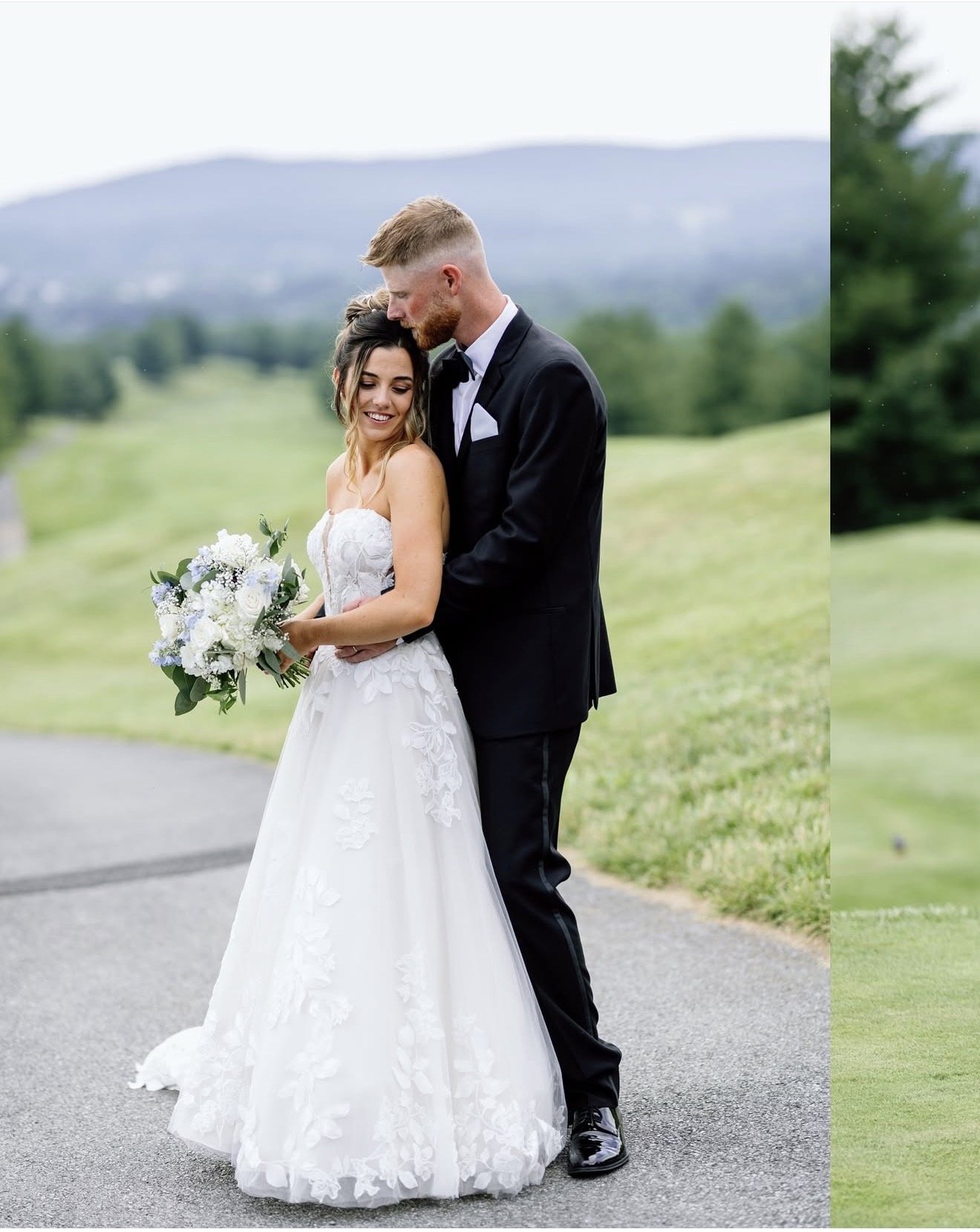 A couple on their wedding day standing in front of a field with a mountain in the background.