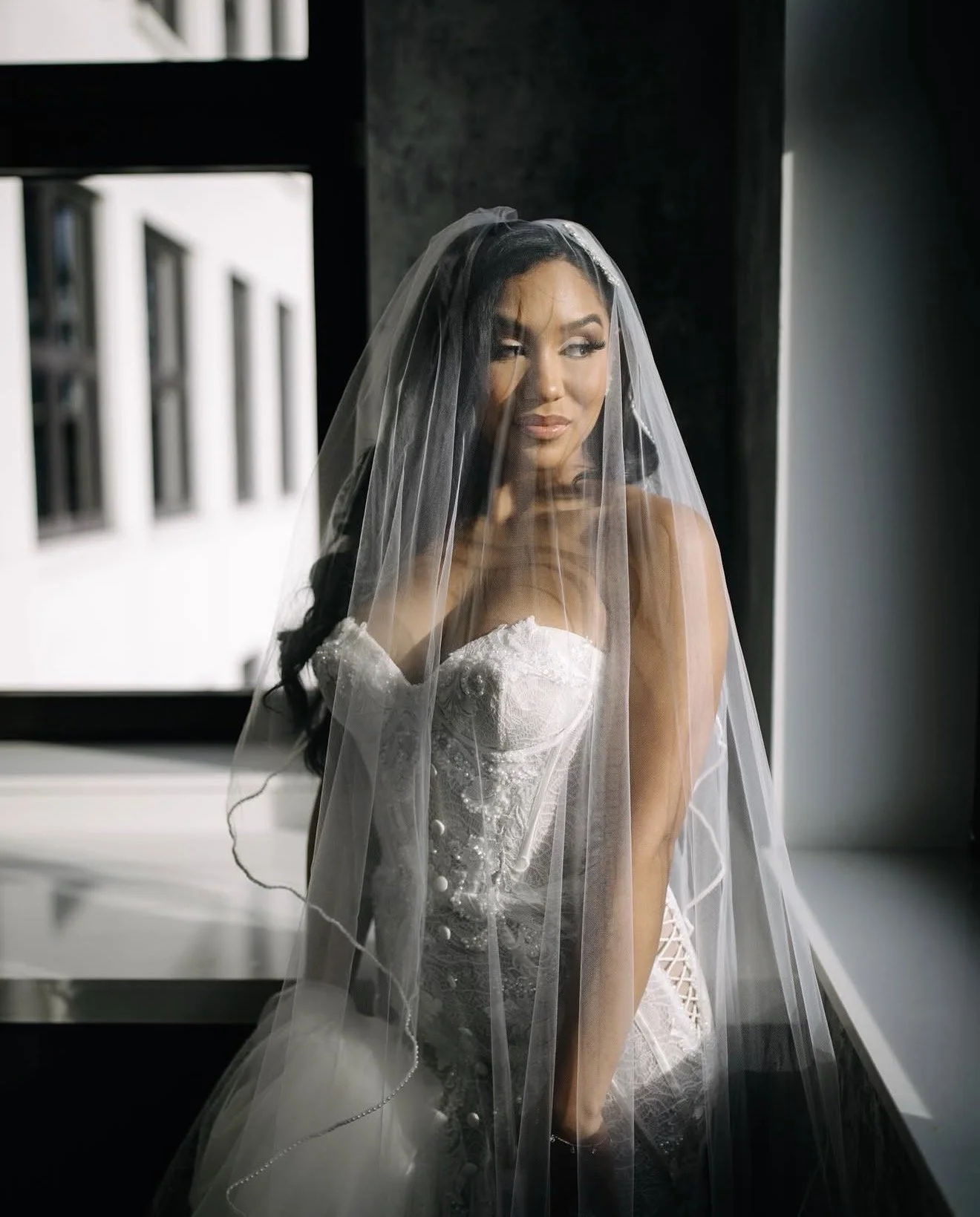 A bride on her wedding day looking off to the side with her veil over her face.