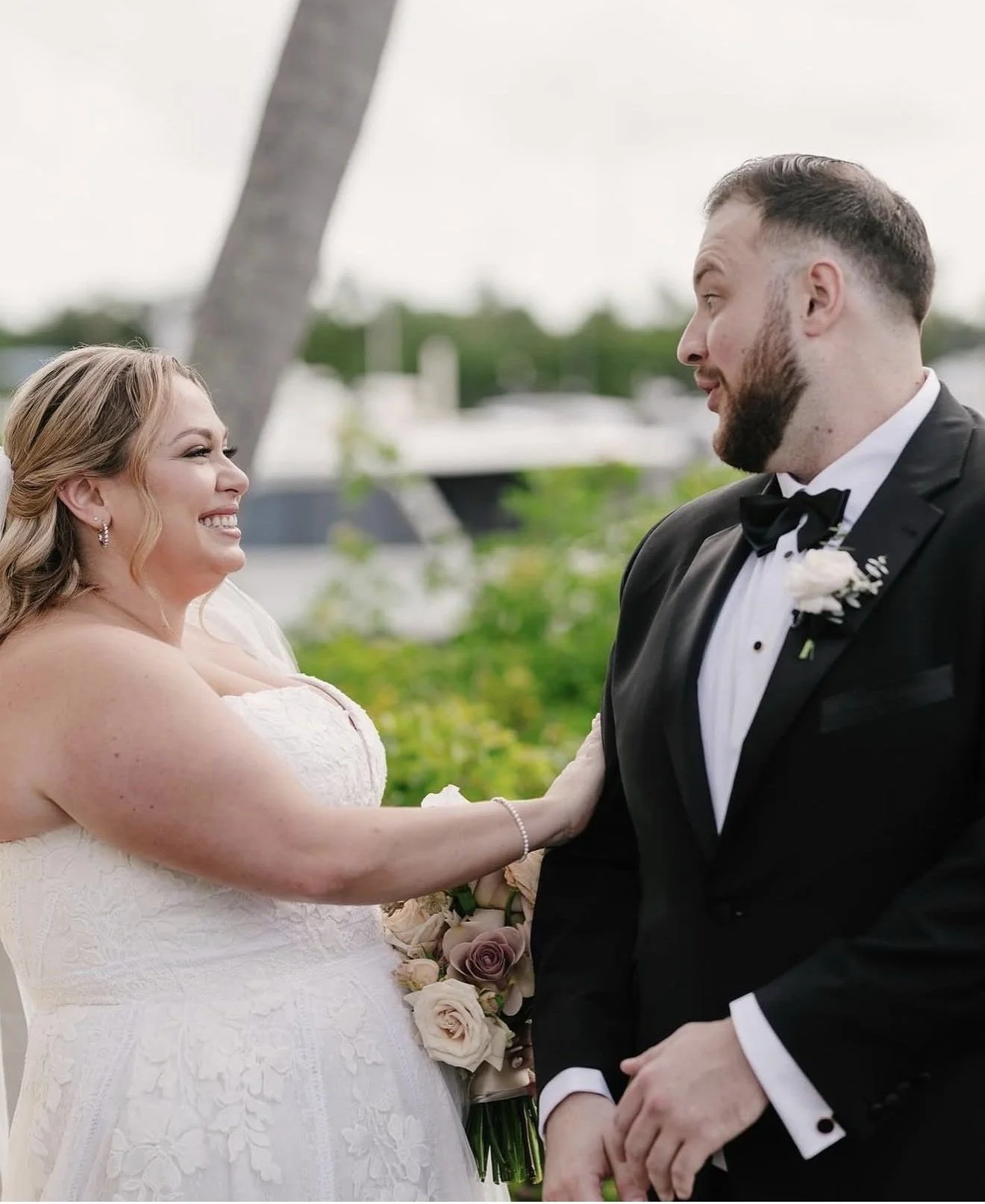 A couple on their wedding day outside smiling at each other.