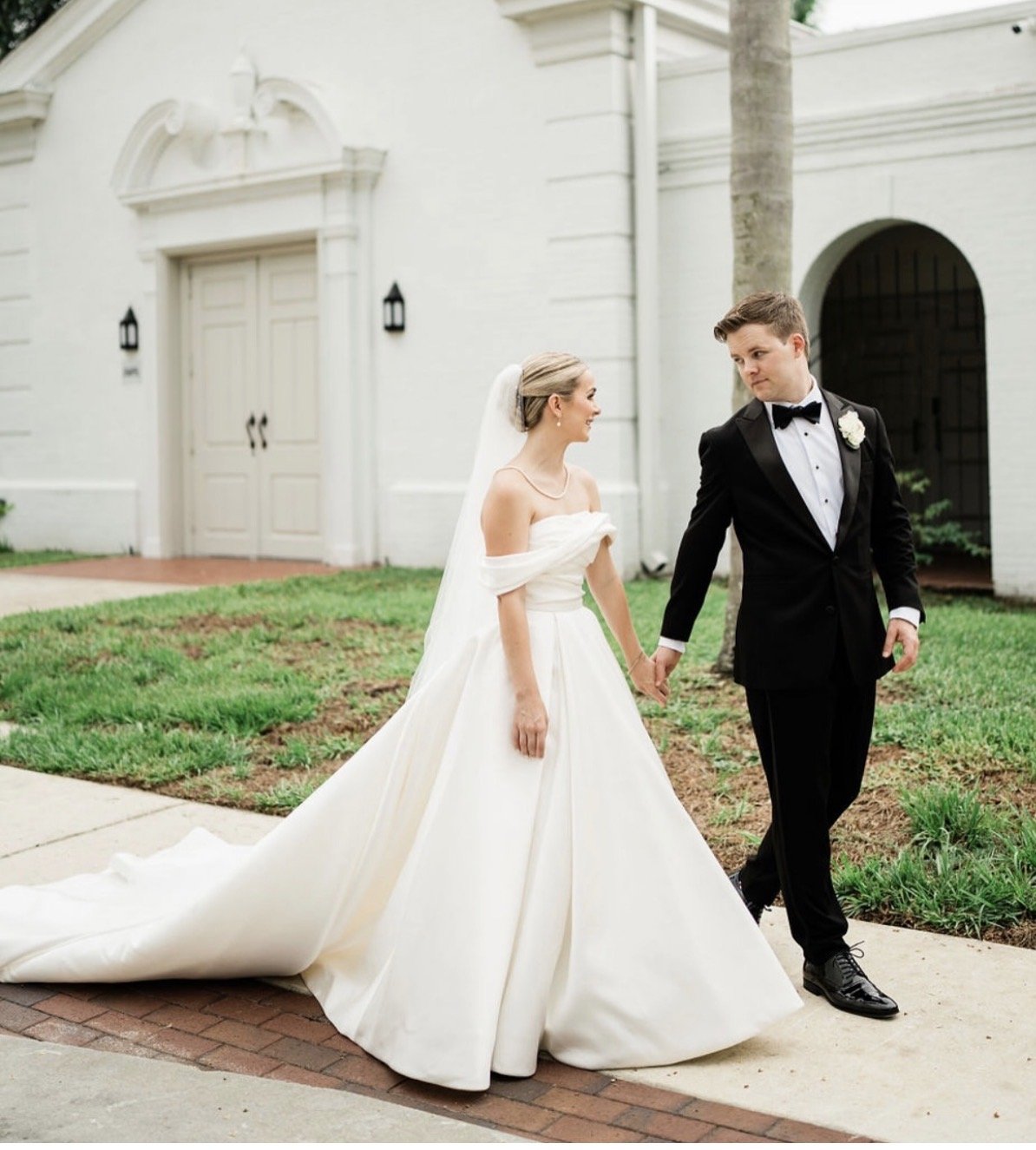 A couple on their wedding day walking in front of a building.