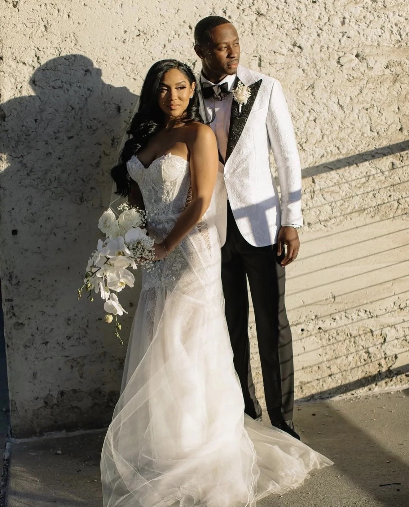 A couple in front of a wall on their wedding day