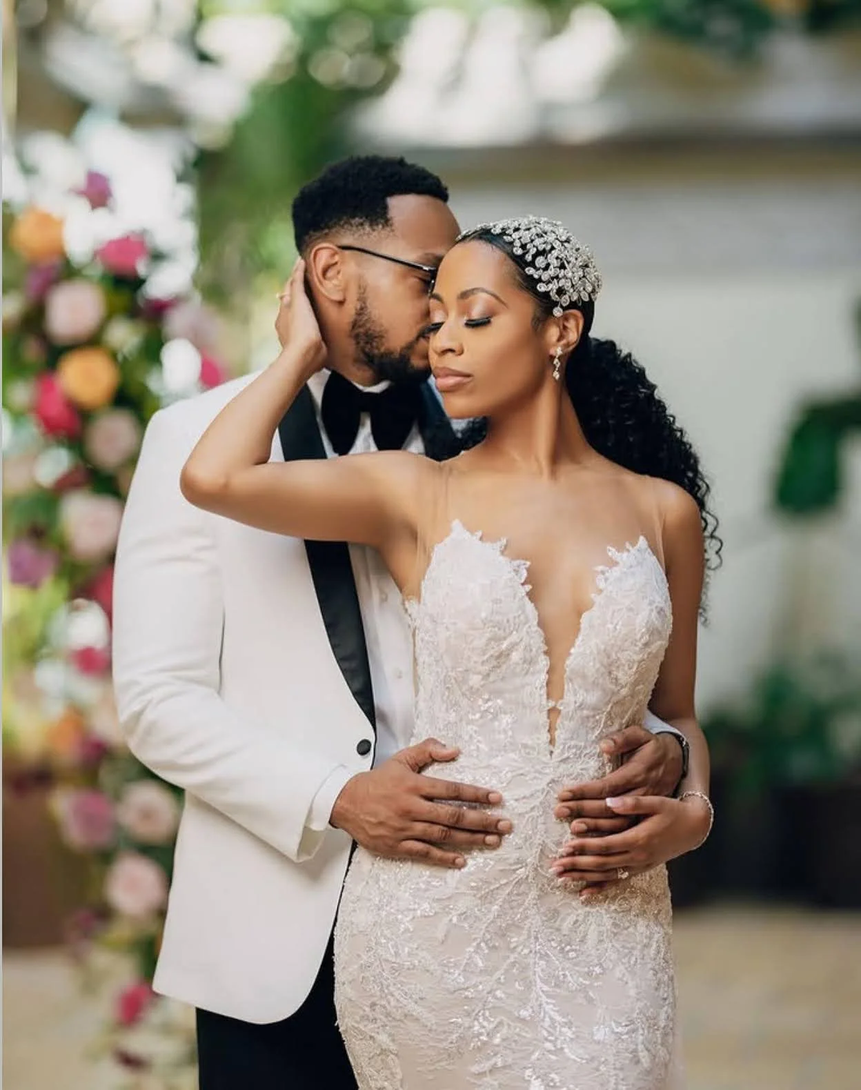 A couple outside on their wedding day in front of flowers. 