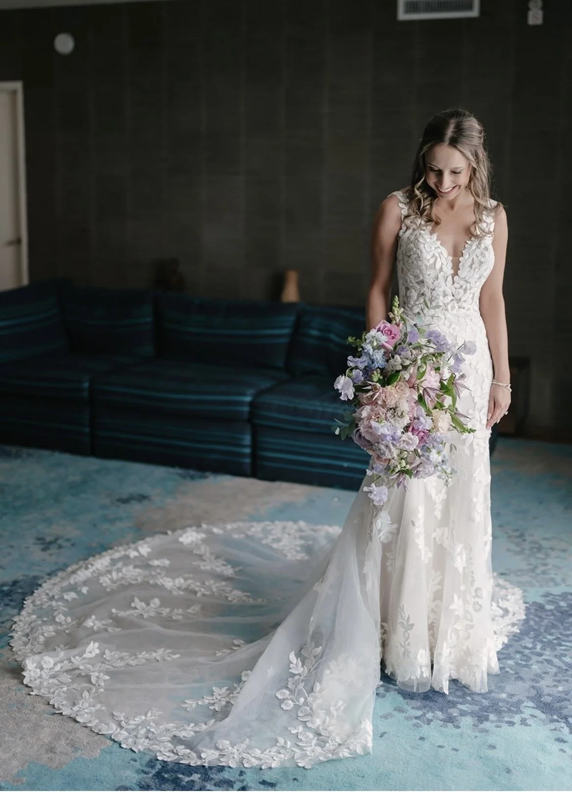 A bride inside looking down holding a bouquet with her train spread out.