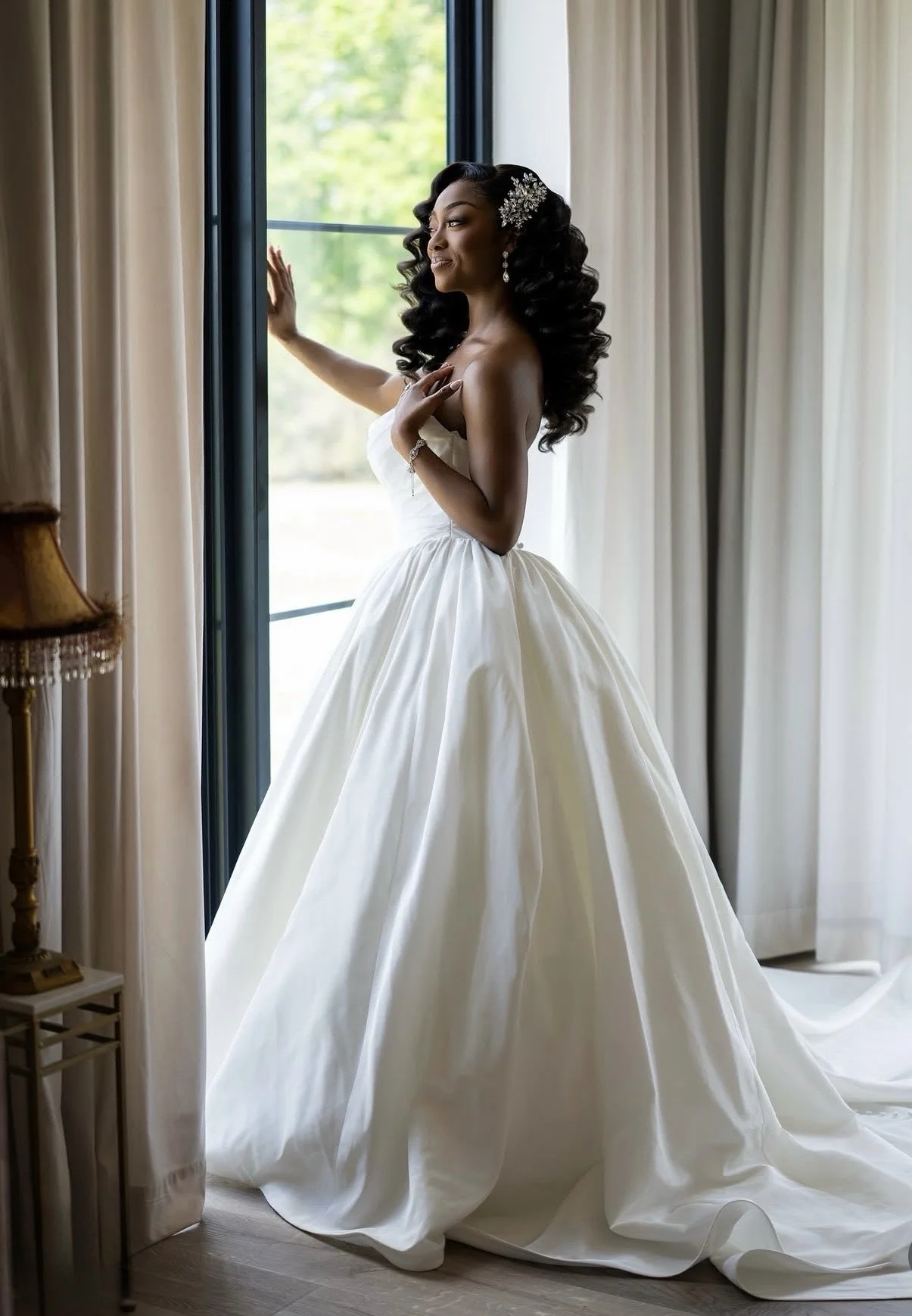 A bride standing indoors in front of a window with pulled back beige curtains.