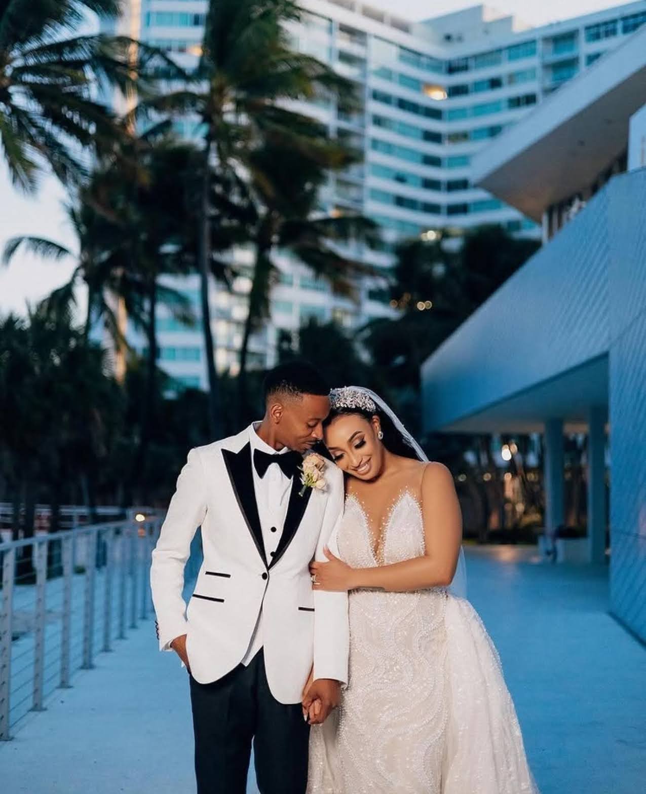 A couple outside in front of palm trees and a building on their wedding day.