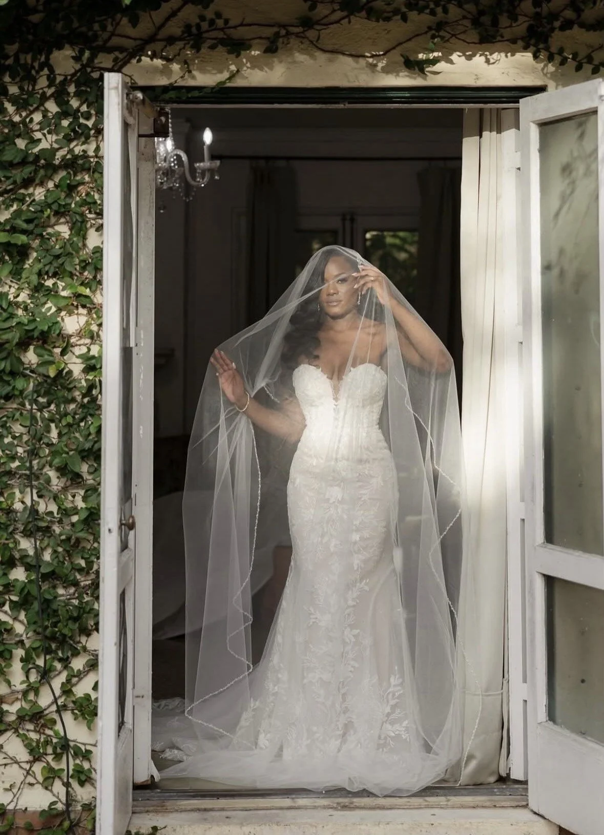 A bride standing in a doorway with her veil over her.