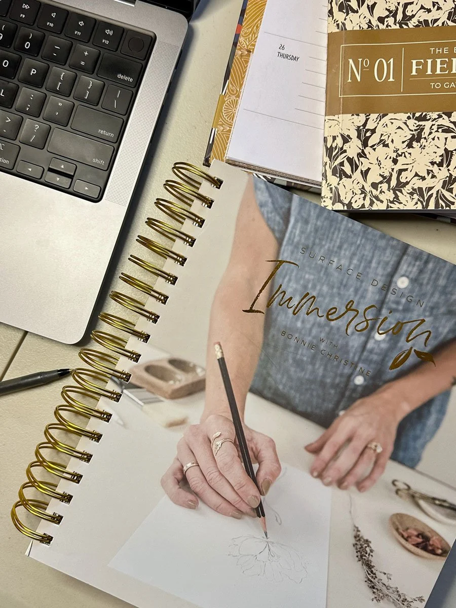overhead view of a table with a laptop and Immersion workbook