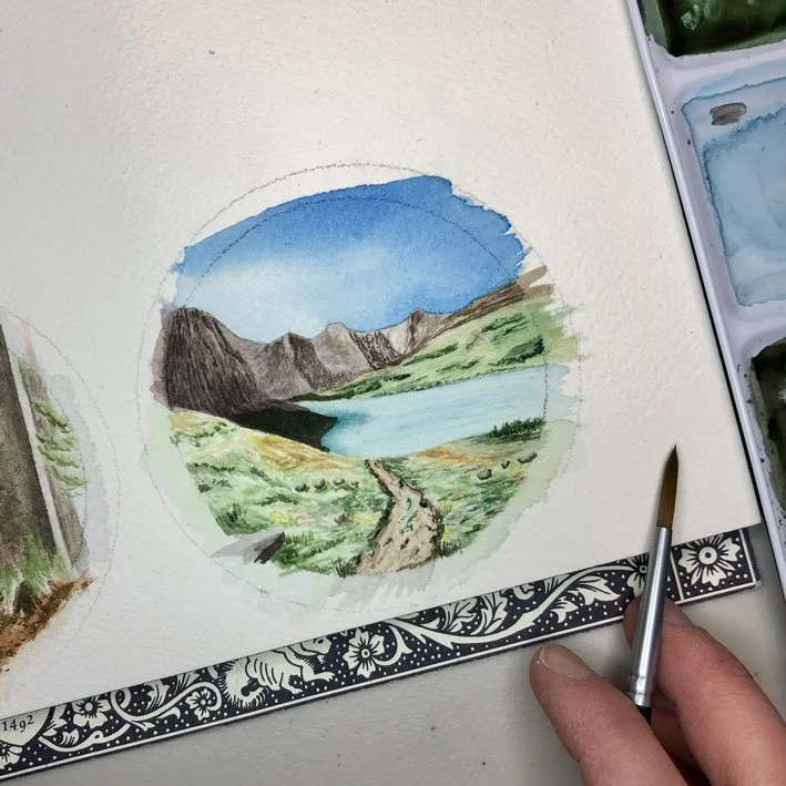round watercolor painting depicting a mountain
