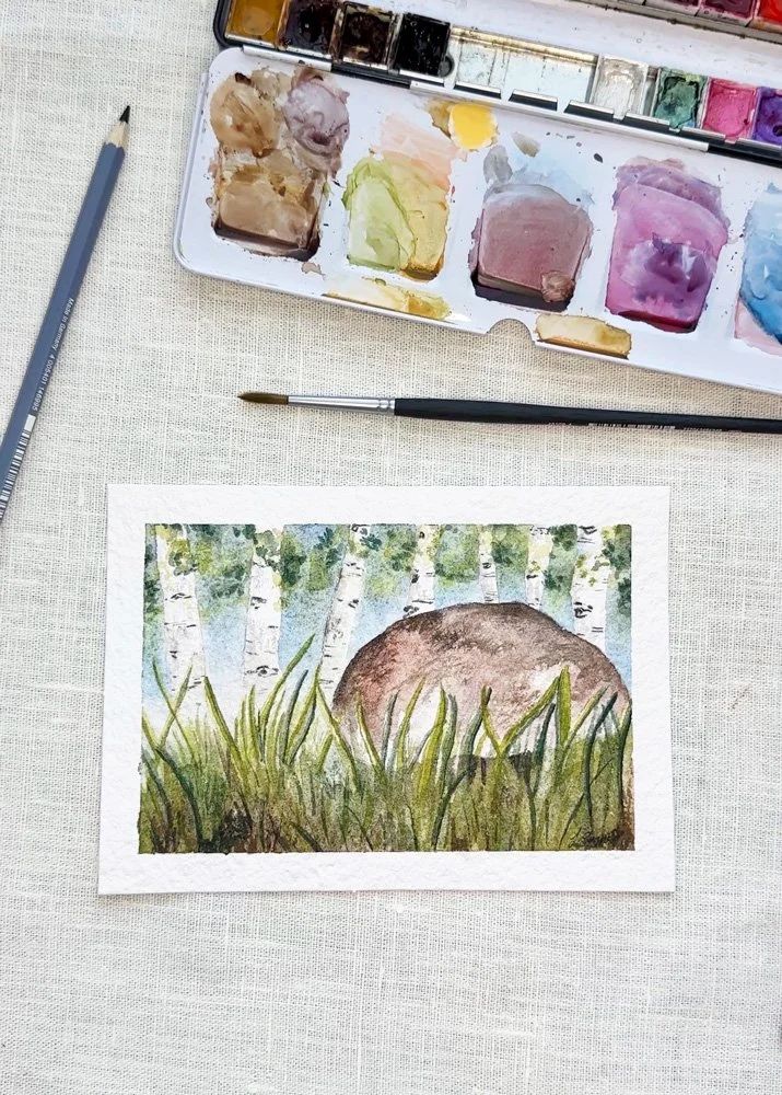 overhead view of a watercolor painting of a mushroom in the grass