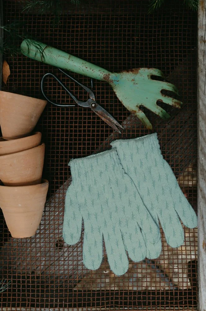 Mockup of garden gloves featuring herb sprigs in green.