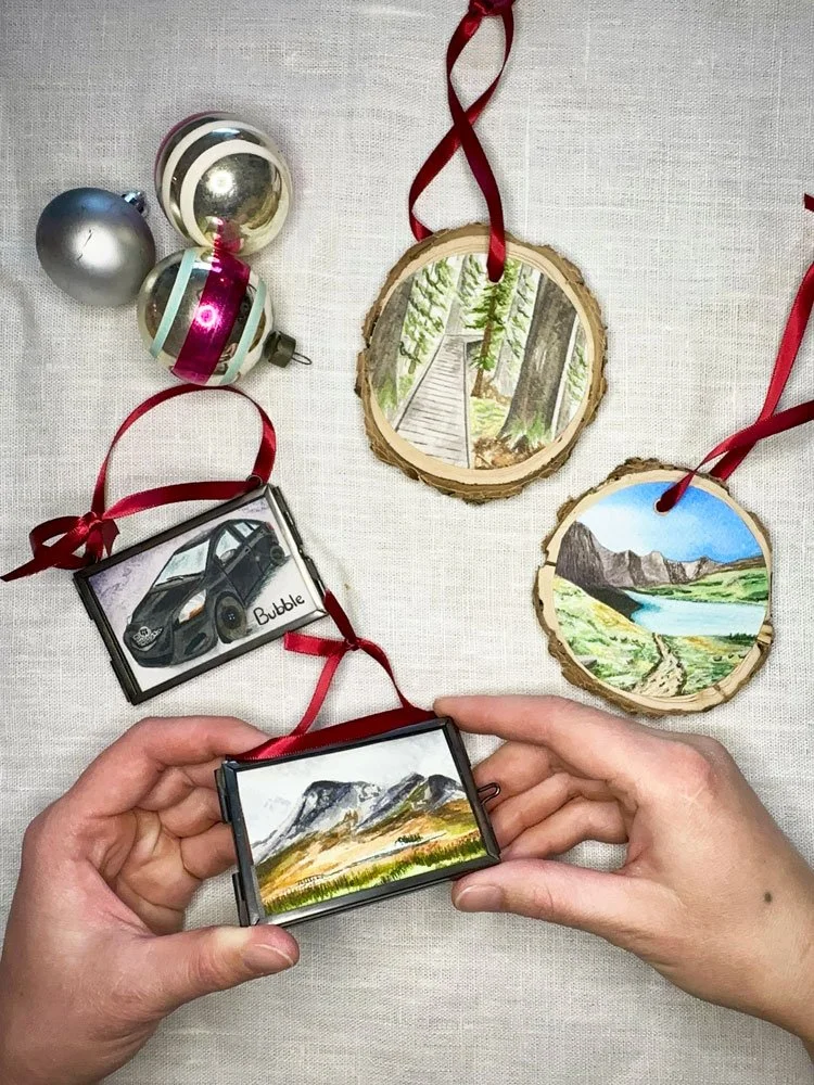 overhead view of handmade ornaments two that are watercolor painting on top of wooden rounds and two in mini glass frames