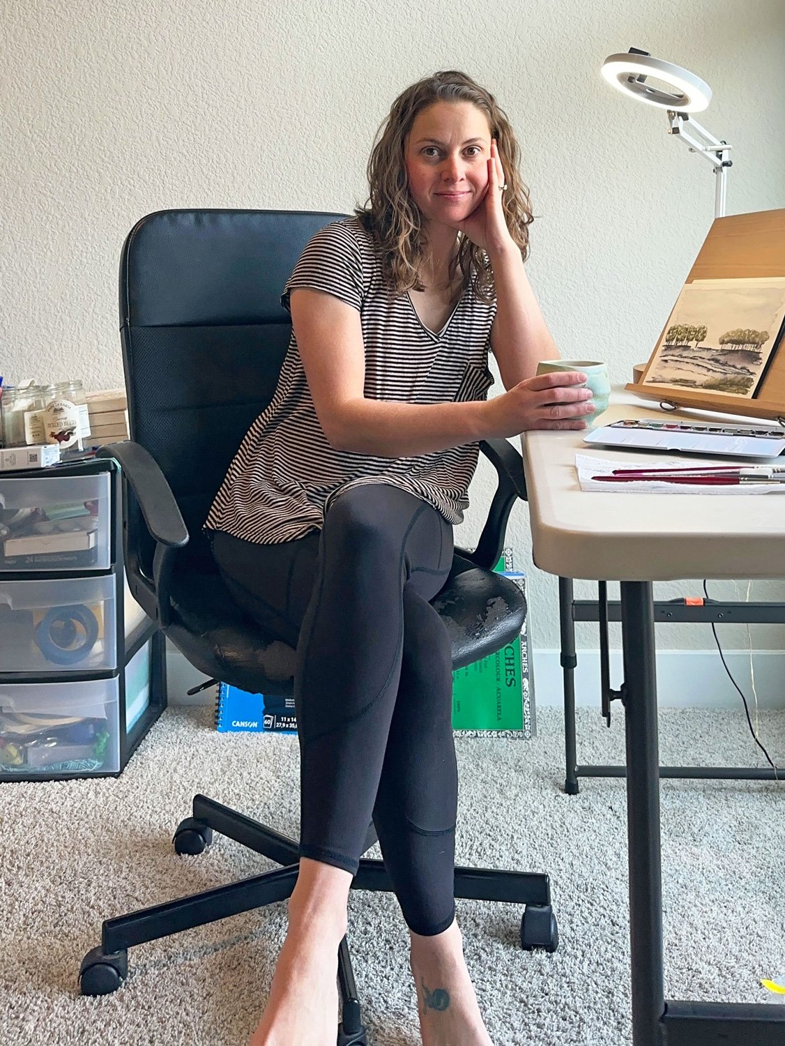 artist Jesse Gagnon sitting at her desk in her studio facing the camera.