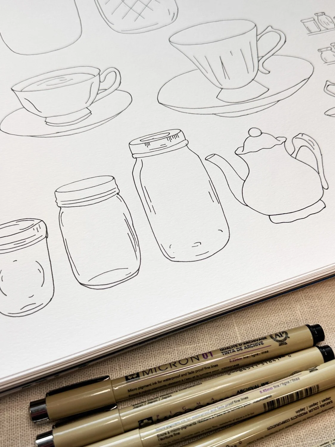 Line drawing of various kitchen items including cups, jars, a teapot, and small containers, with four beige markers placed below.