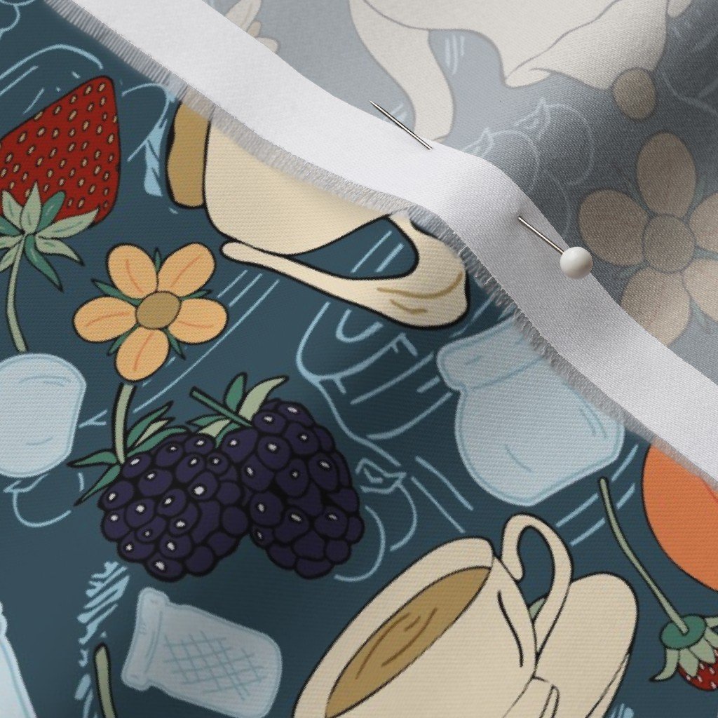 Patterned fabric with illustrations of strawberries, blackberries, flowers, mugs, and milk containers, with a straight pin secured on a white ribbon.