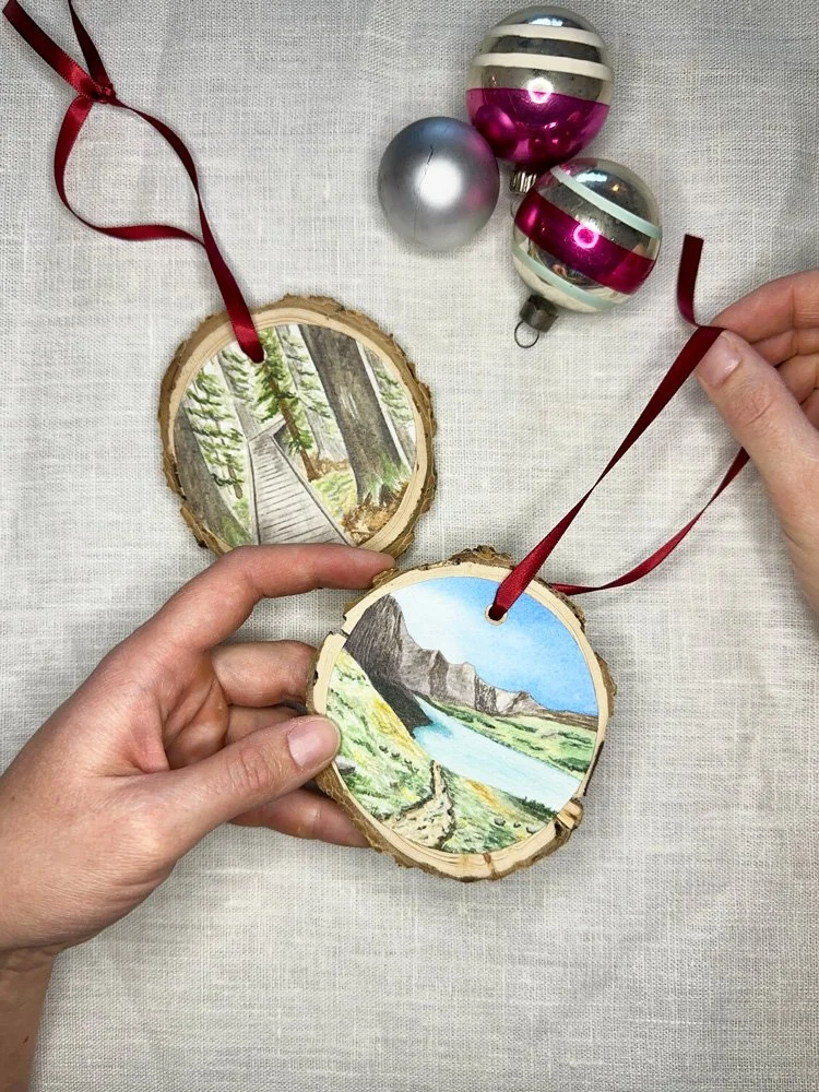 two watercolor ornaments mounted onto a a wooden round.