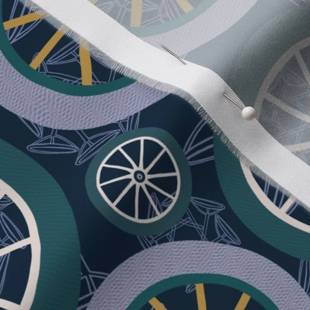 Close-up of a sewing machine working on fabric with a pattern of clocks and wheels, with visible pins holding the fabric in place.