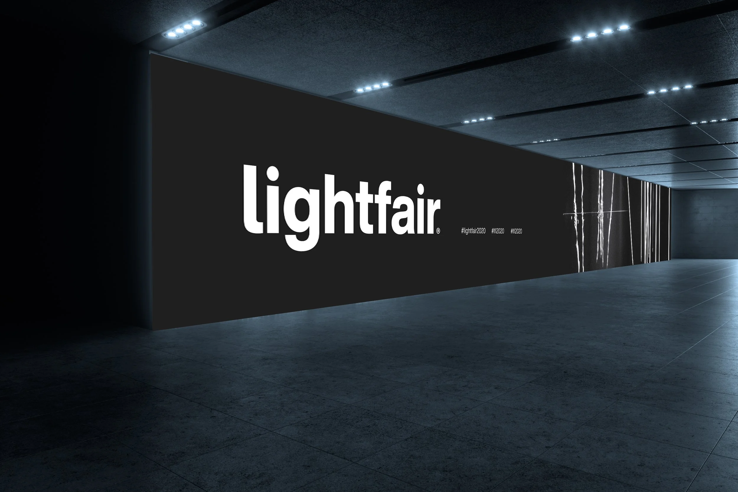 A modern conference or event space with dark walls and ceiling, illuminated by recessed lights. There is a large black wall with white text that reads 'lightfair' and hashtags #lightfair2020, #lf2020, and #lf2020. The floor is dark and reflective, with a marble-like column visible in the background.