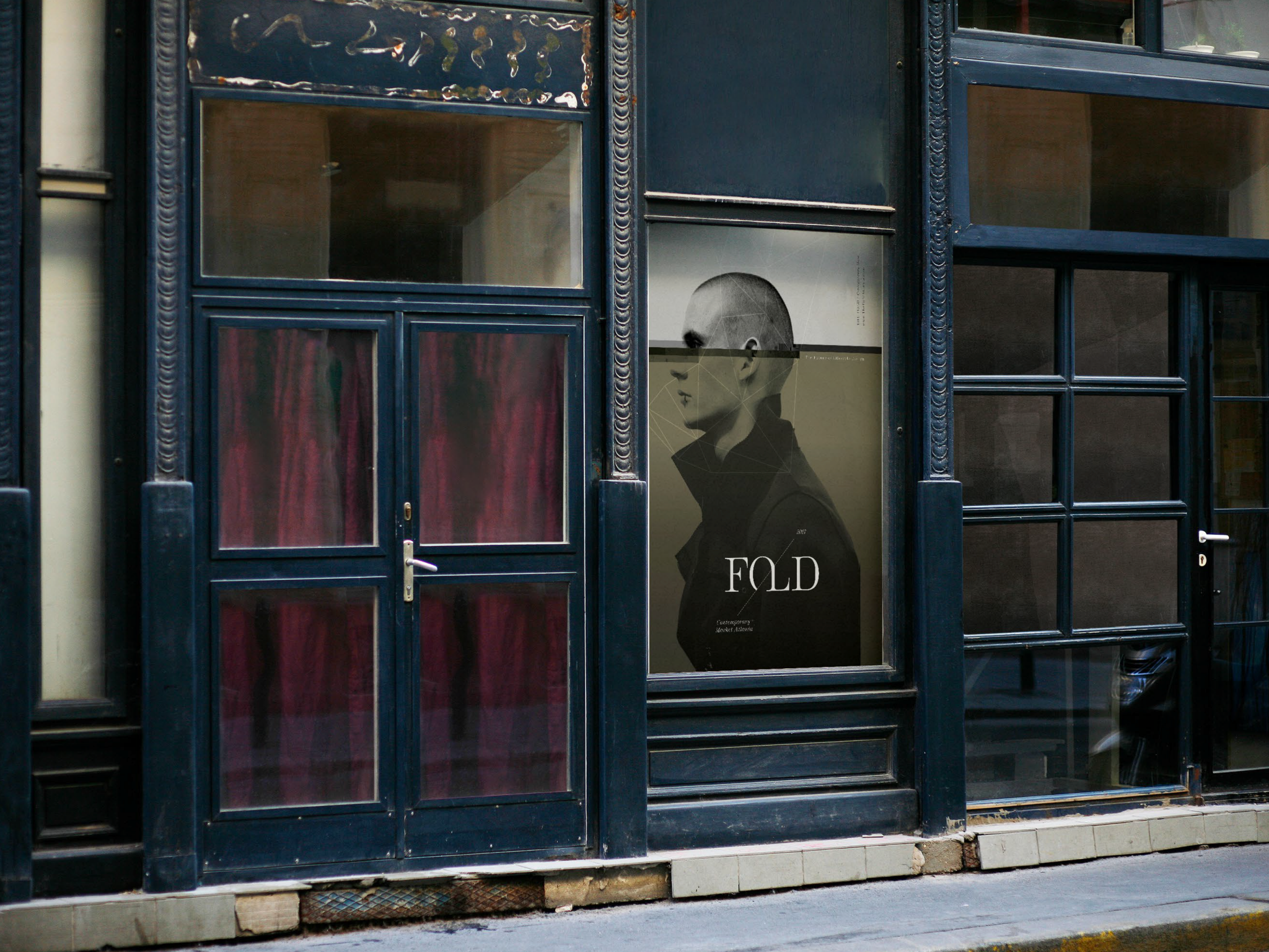 View of storefront window with a poster featuring a woman's profile, geometric lines, and the word 'FOLD' at the bottom.