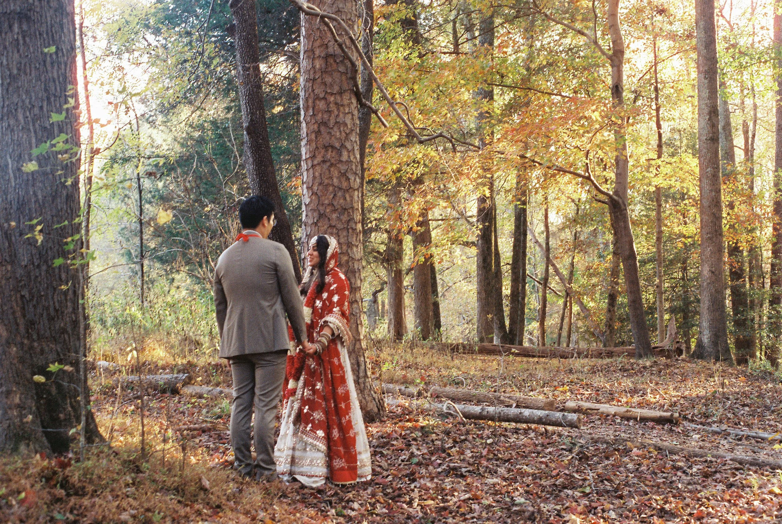 couple standing in fall colored trees on their wedding day on film