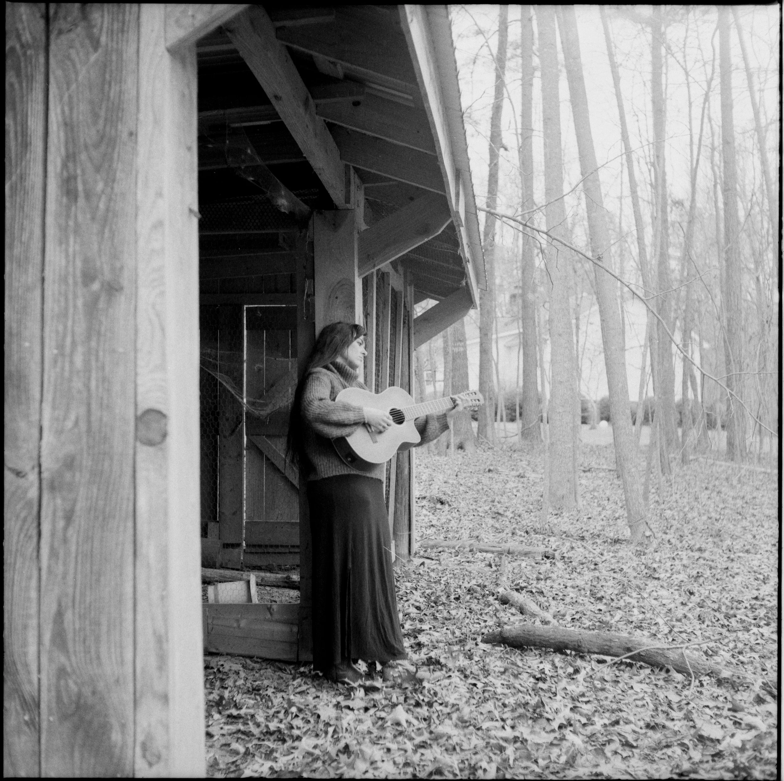 anna playing her guitar by an abandoned shed in the mountains on film