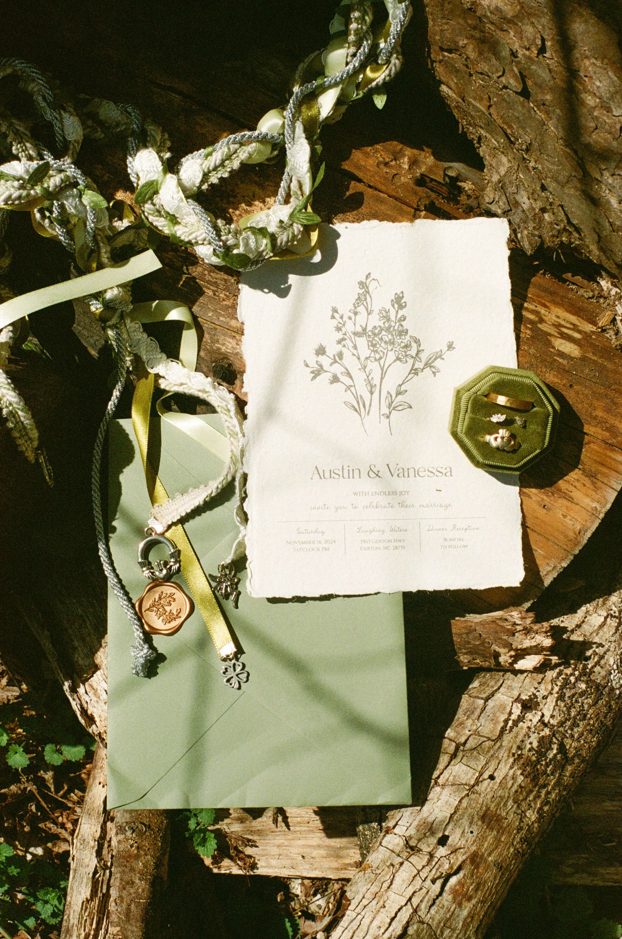 flat lay image of couple's wedding suite and invitations with the celtic rope on a wooden log