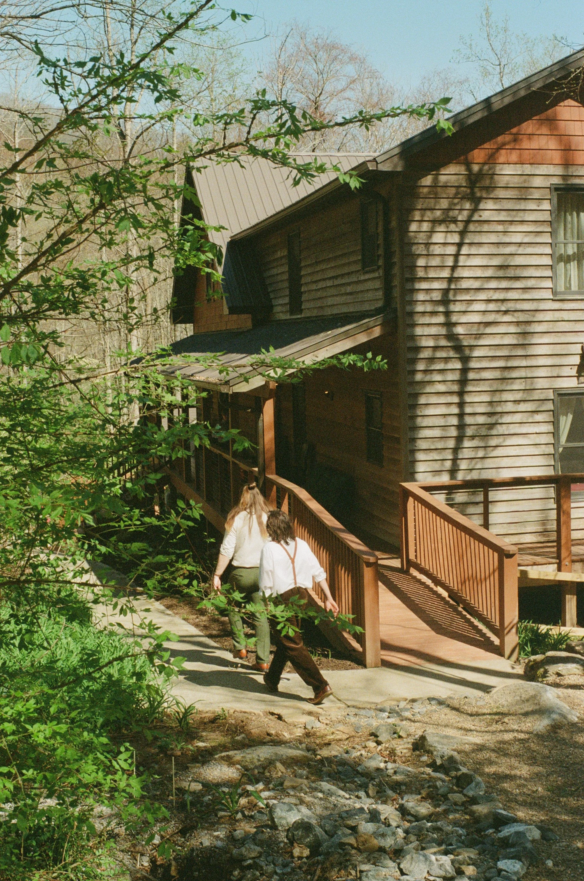 two men walking with cabin in the background on a summer wedding in gerton north carolina