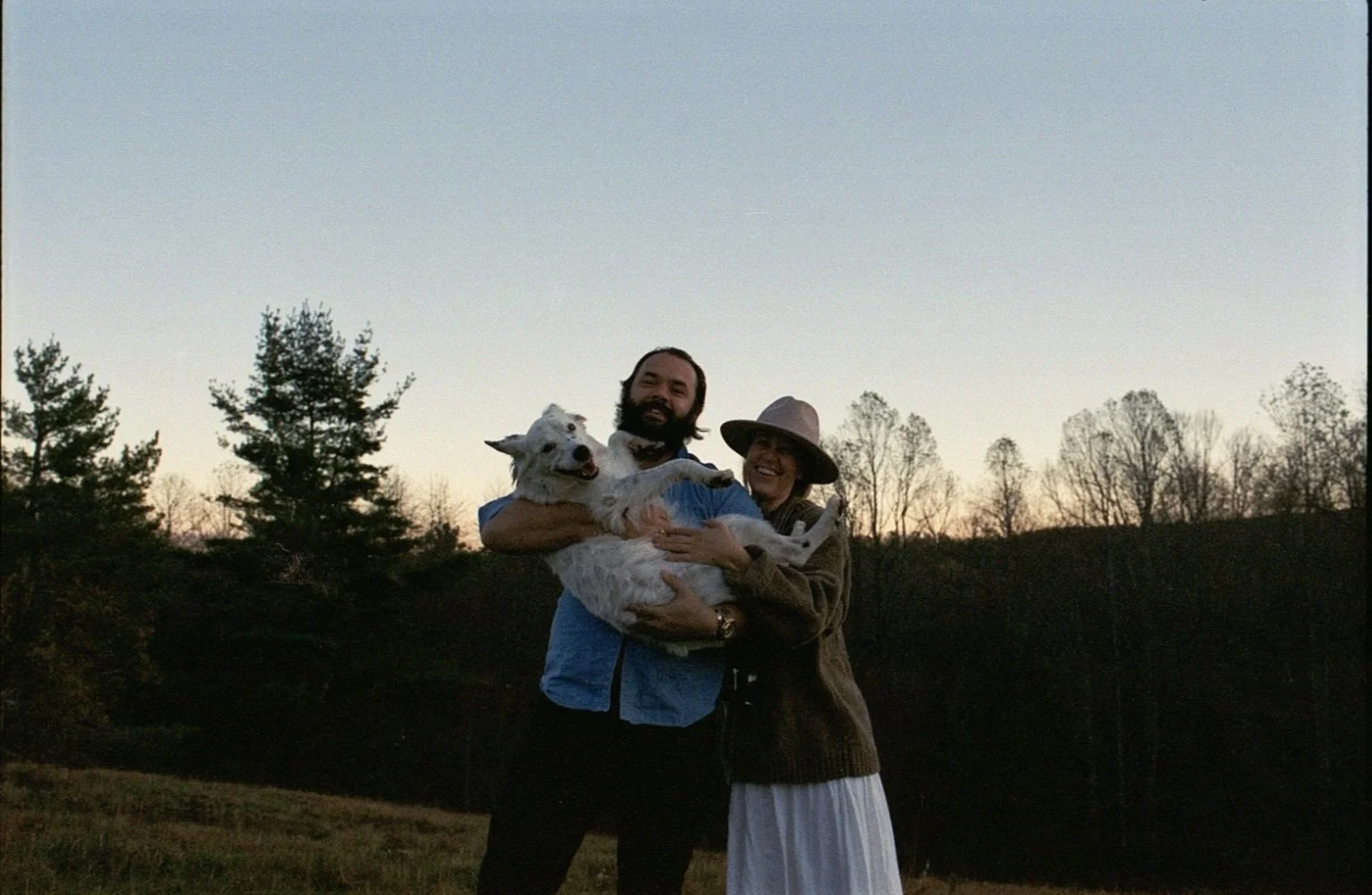 couple smiling holding their puppy during engagement shoot