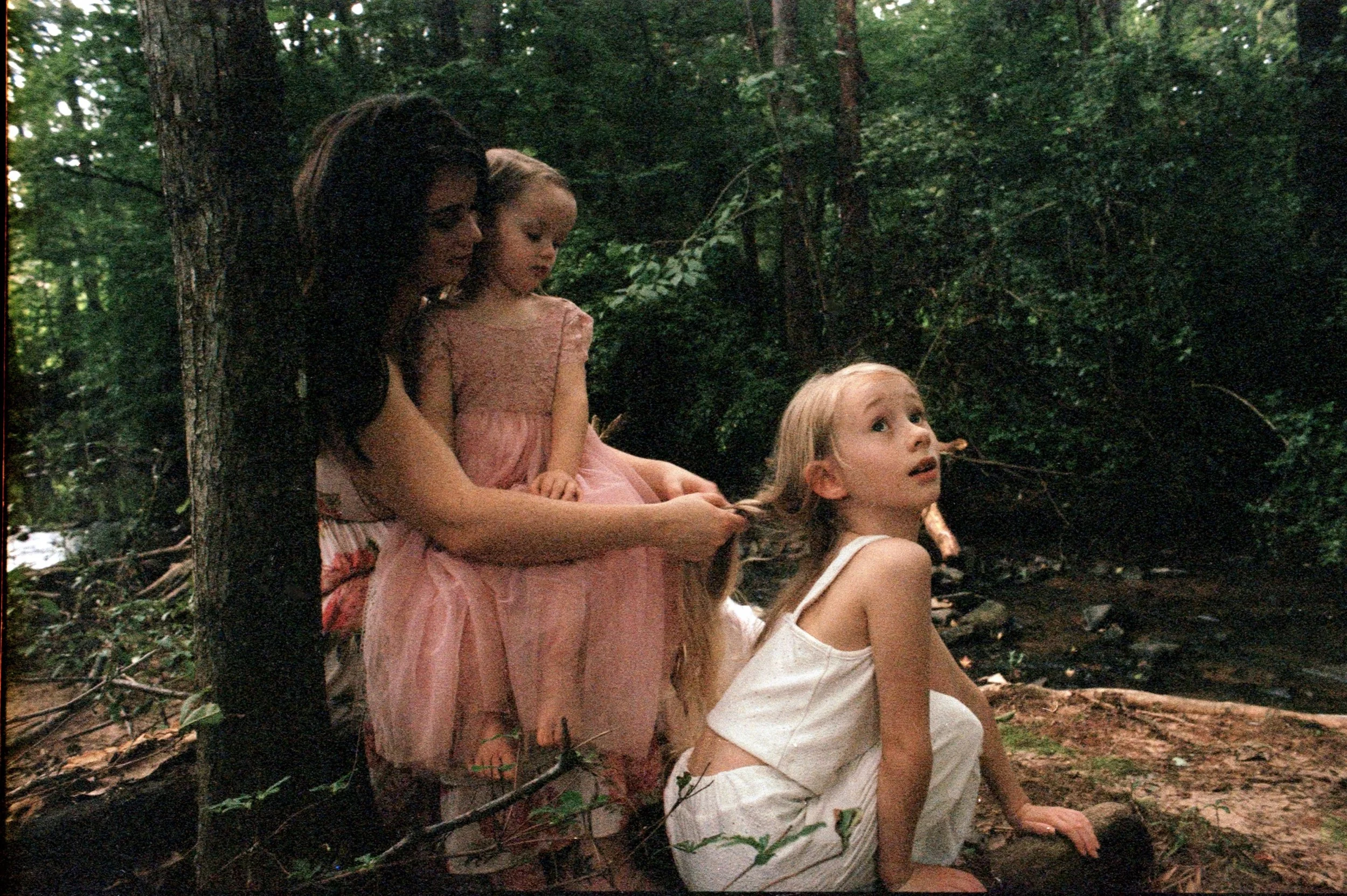 whimsical mother daughter braiding hair in the woods on film