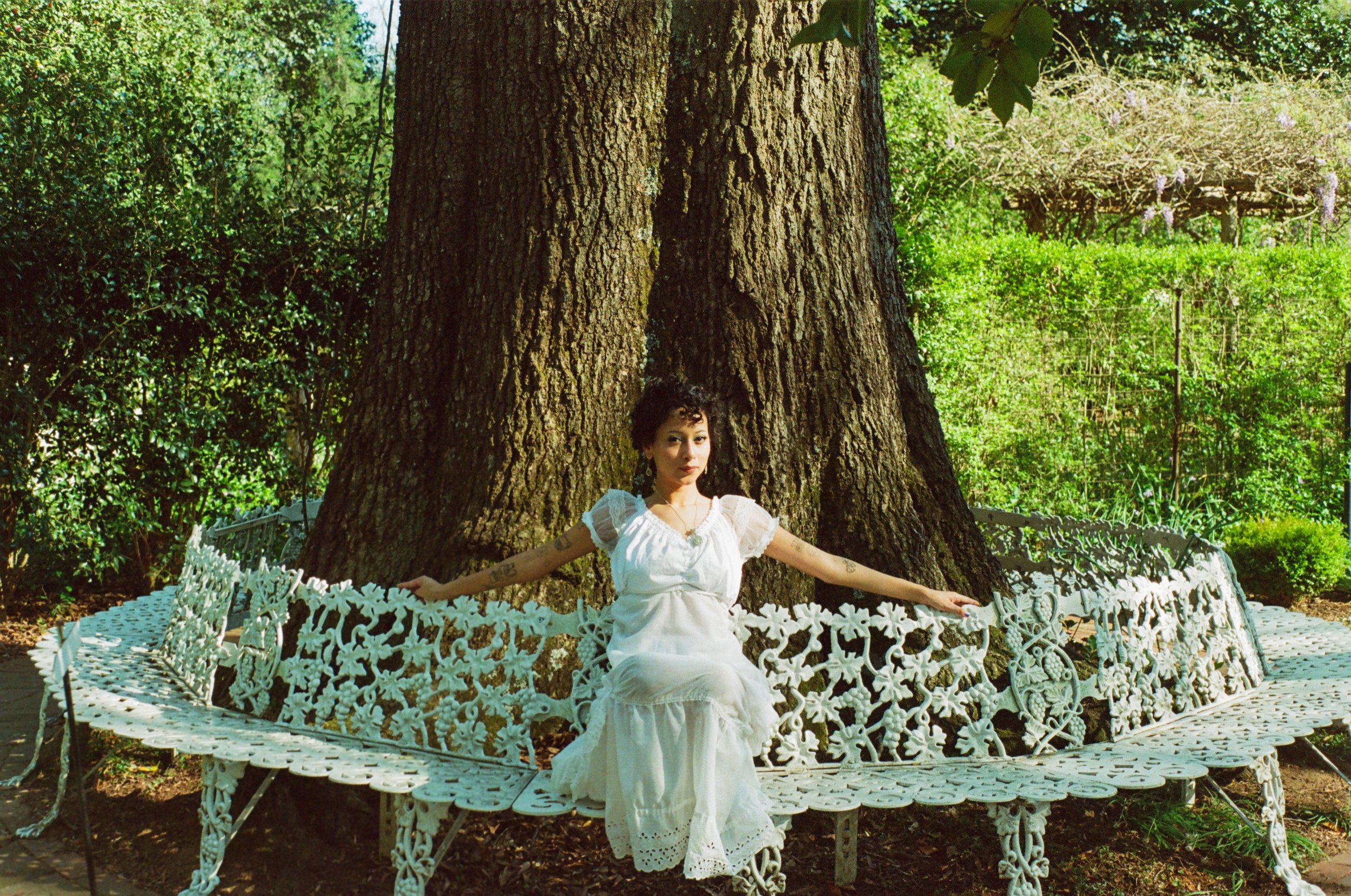 woman sitting on bench posing in the garden on film