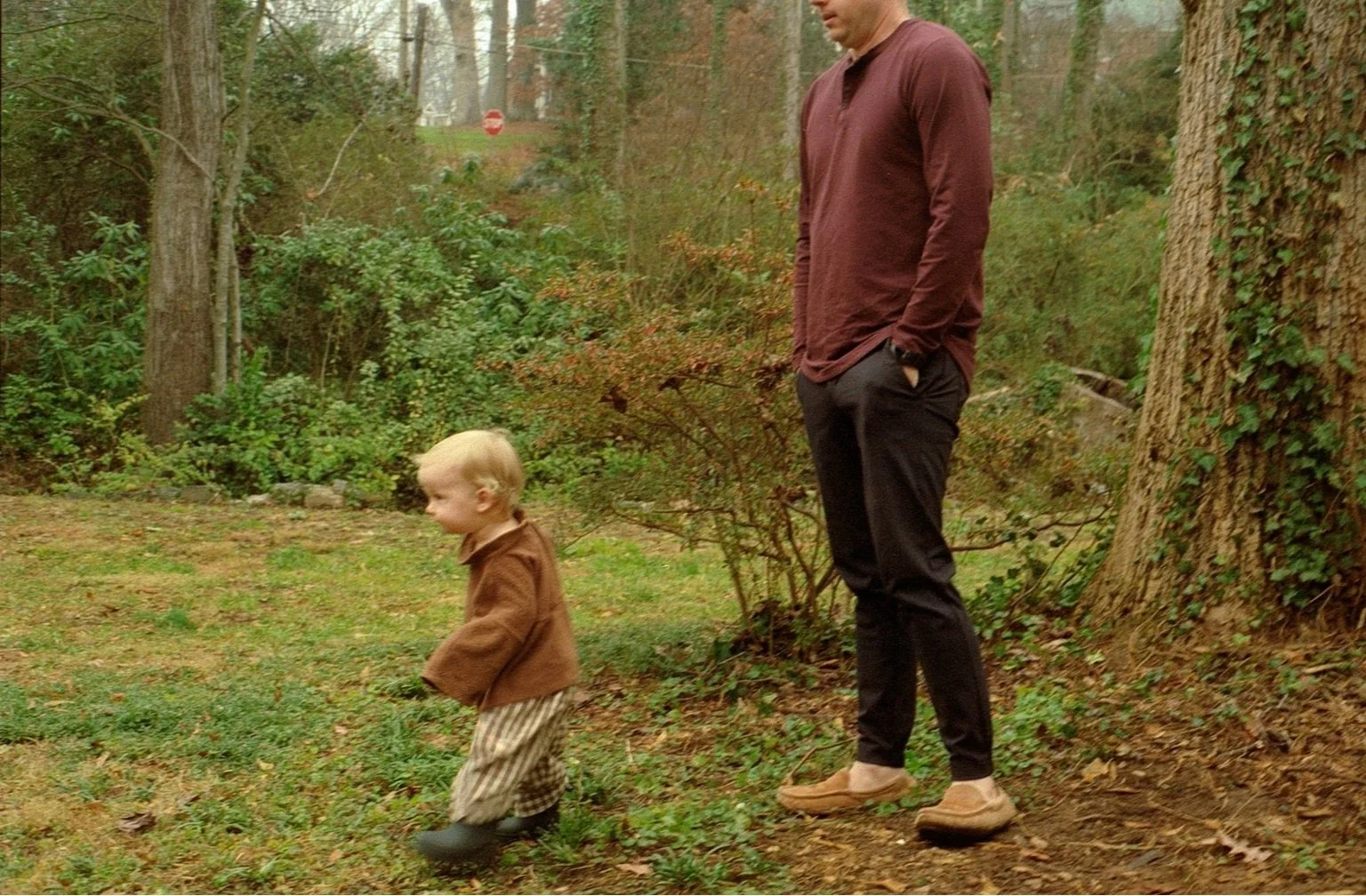 father and son walking in front yard on a rainy day on film