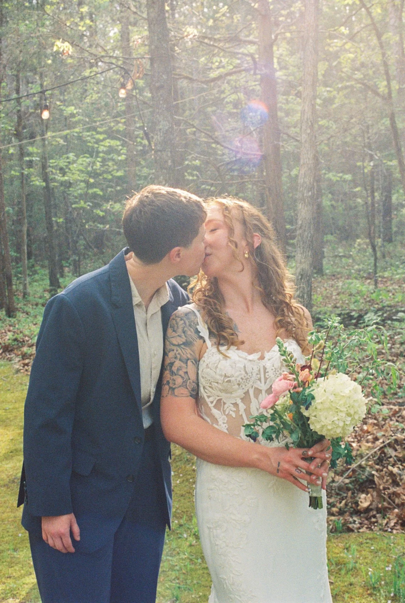 brides kiss after ceremony in the woods