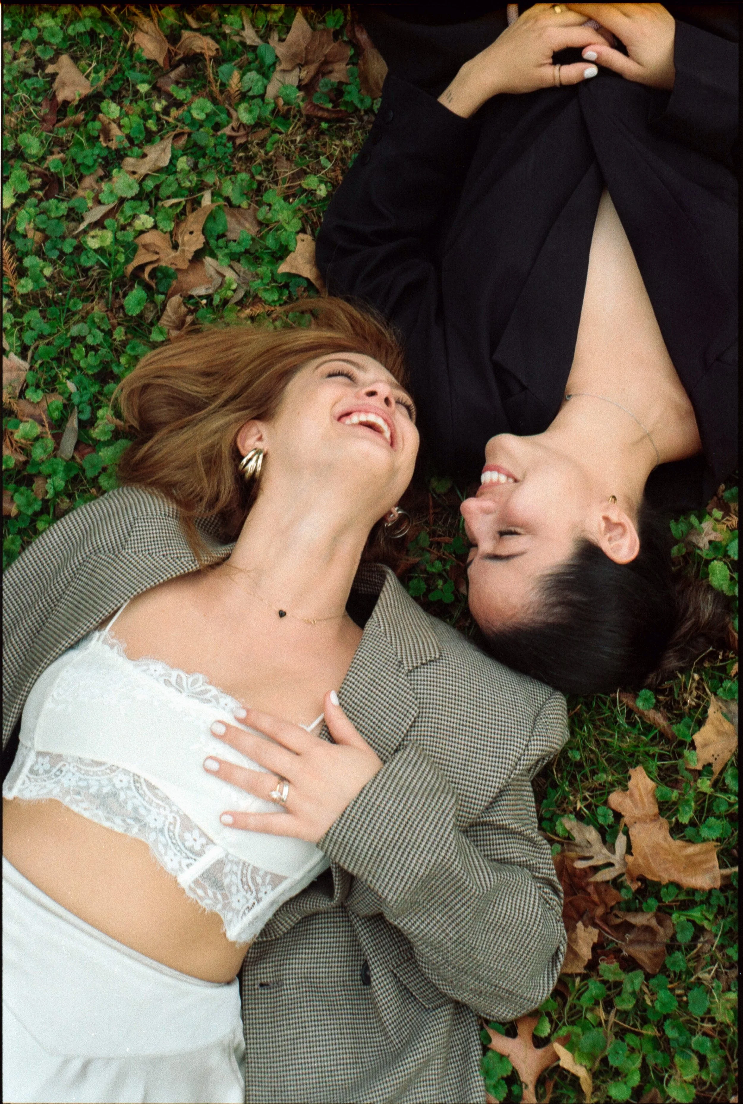 couple smiling laying on the ground for their engagement shoot at asheville botanical gardens