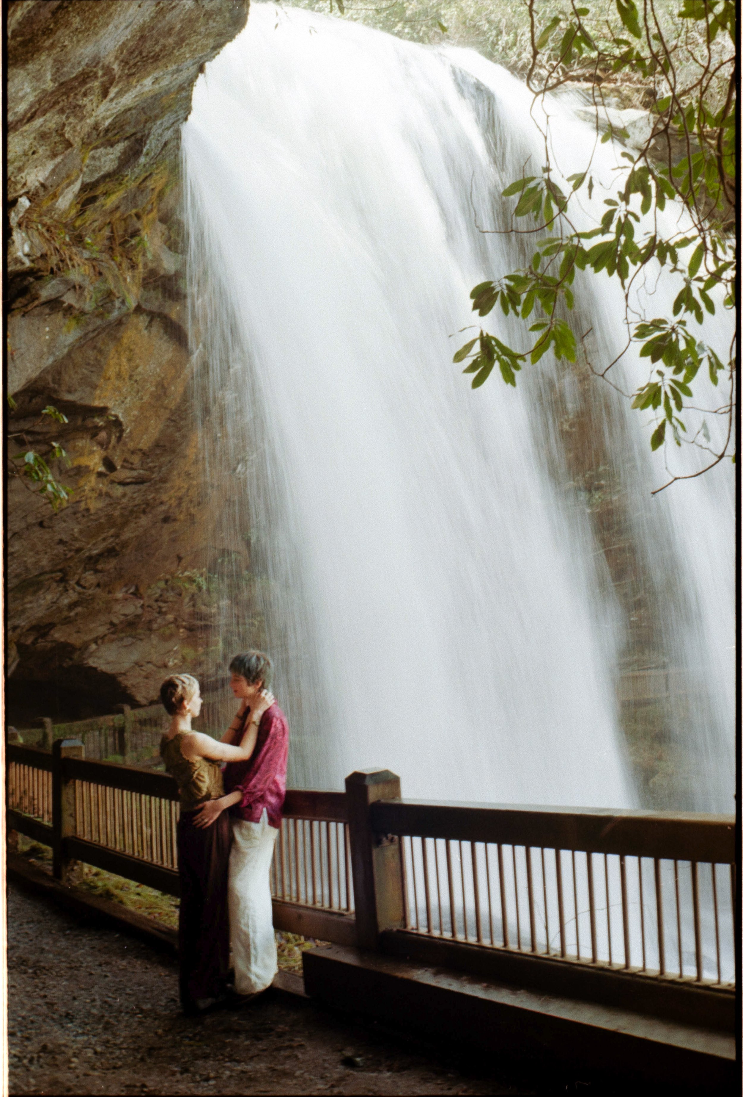 couple standing behind waterfall in highlands north carolina mountains