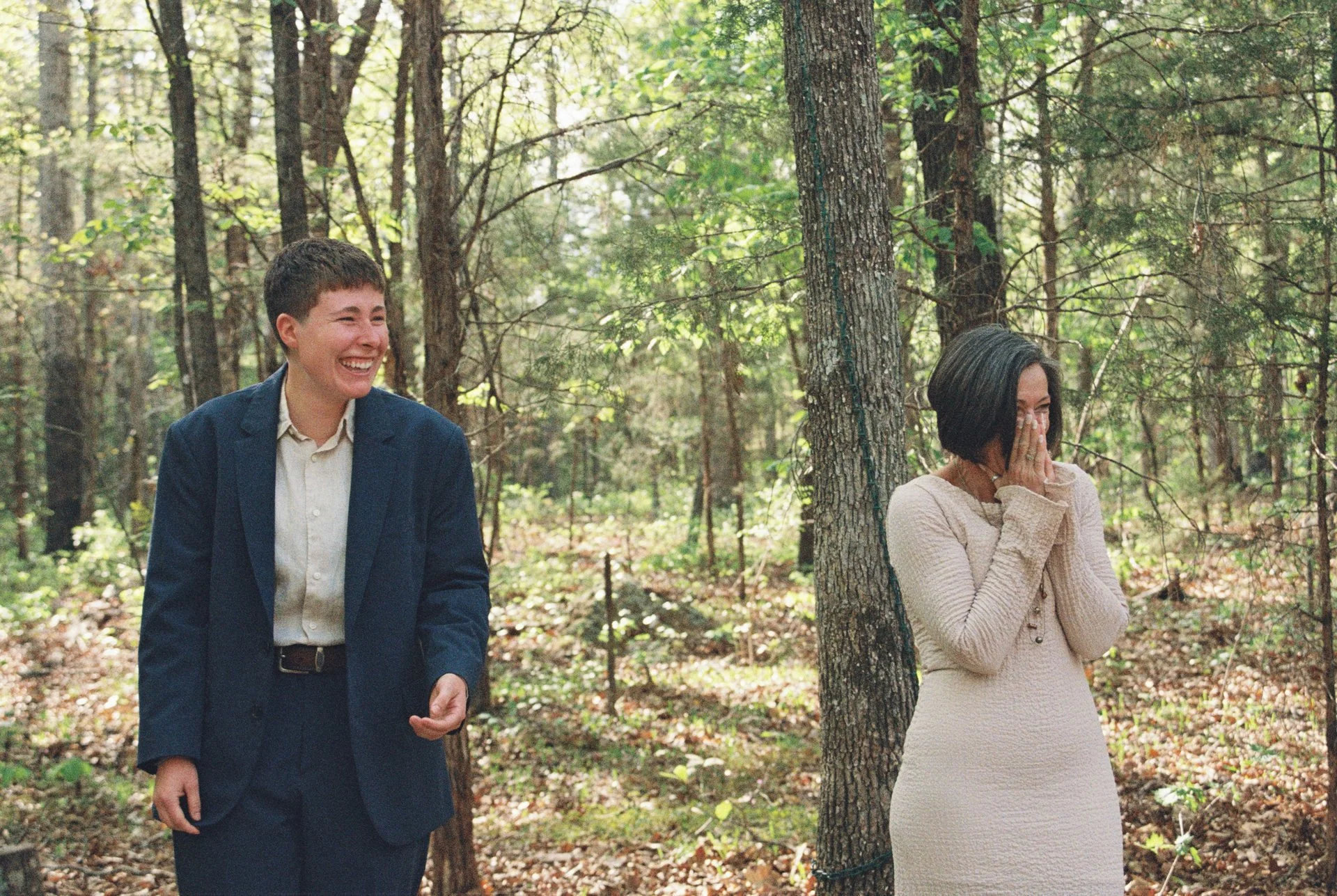 bride and mother laughing at flower girl walking down the aisle
