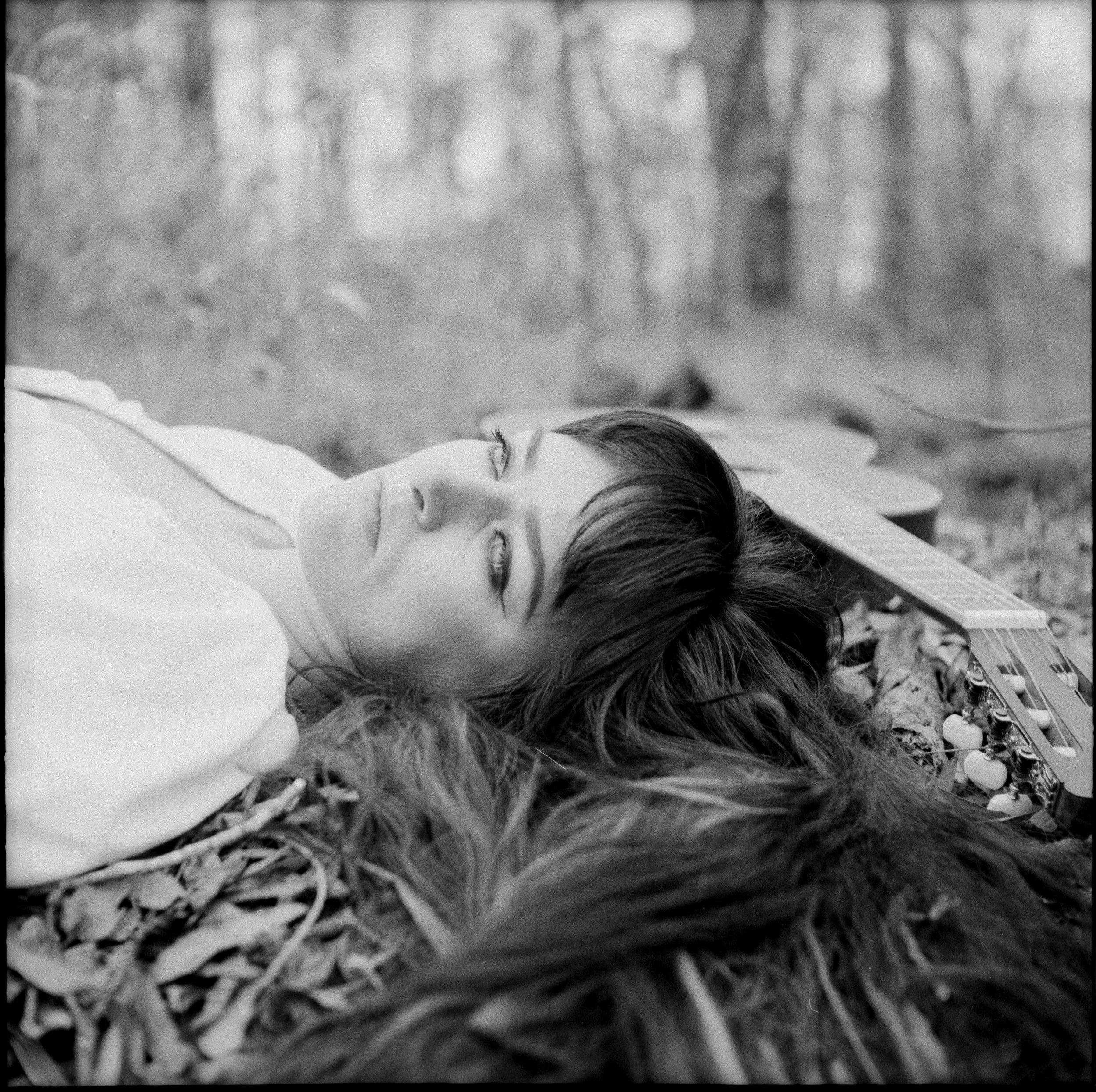 girl laying down looking longingly up with guitar in the background