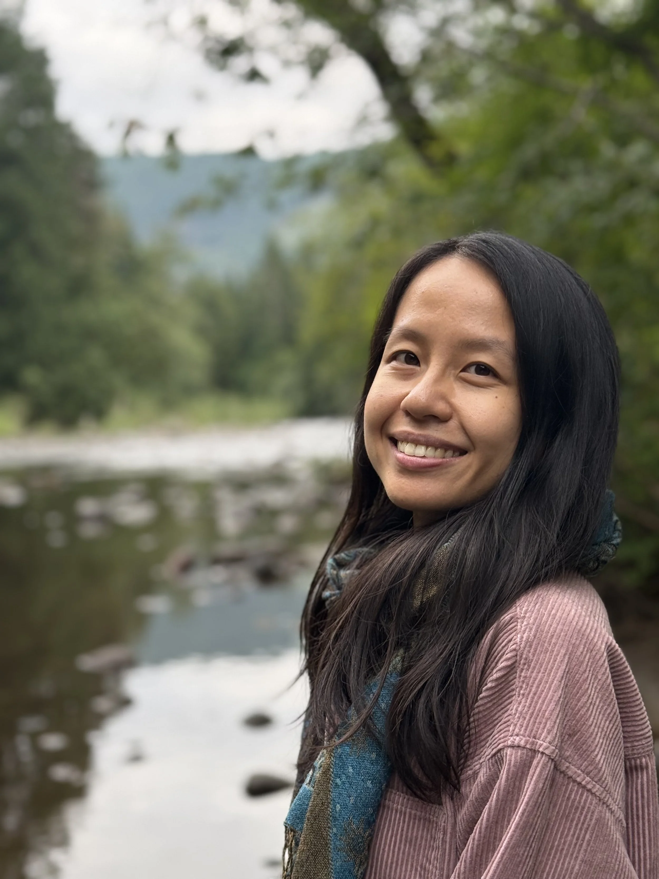 liz zhou, therapist in colorado, smiling next to creek